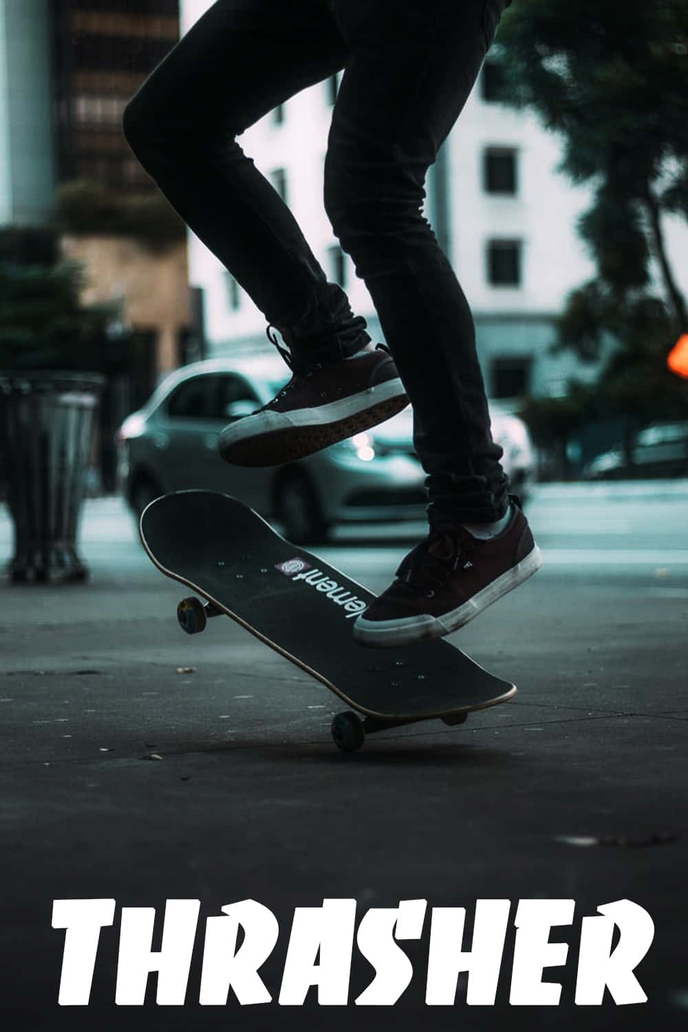 Thrasher 桌布 壁紙 — 一名滑板手在半空中於城市街道上表演技巧，背景有模糊的汽車和建築物。