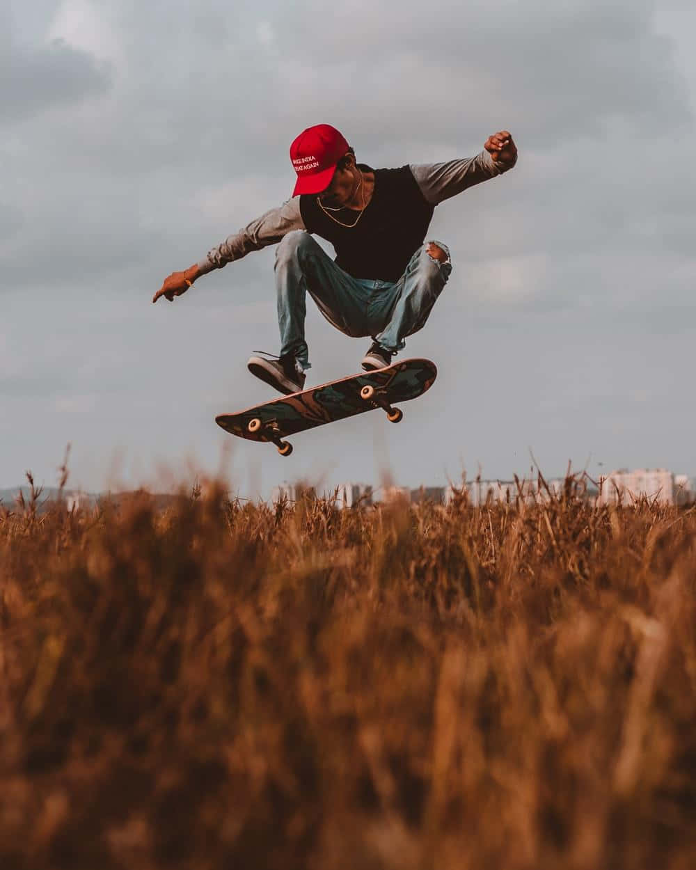 skateboarding 桌布 壁紙 — 一名滑板手在陰天下的金色麥田上空騰空。