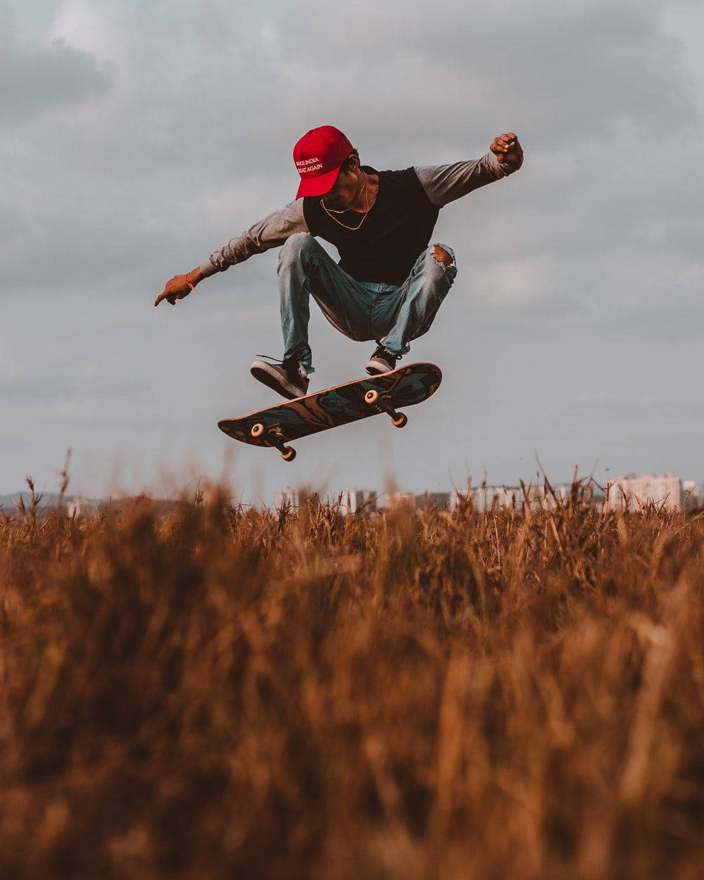 skate 桌布 壁紙 — 一名滑板手在陰天下的金色麥田上空騰空。