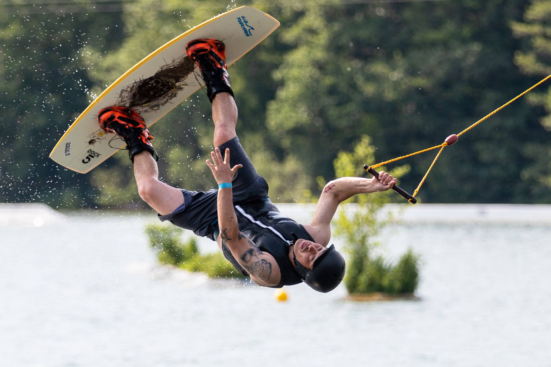 surfing 桌布 壁紙 — 一名滑水板運動員在明亮的日光下，於森林環繞的湖泊上空表演倒轉空中技巧。