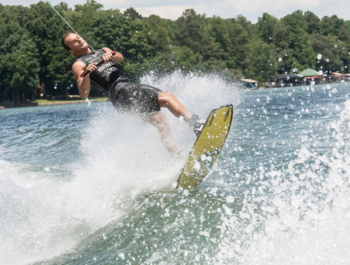 surfing 桌布 壁紙 — 一名滑水運動員在黃色滑板上傾身進行急轉彎，濺起白色水花，背景是綠樹和明亮的天空。