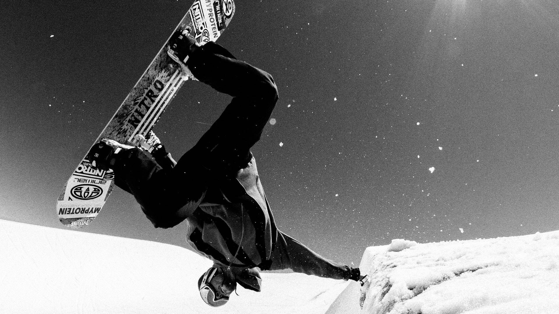 Snowboarding 桌布 壁紙 — 一名滑雪板運動員在明亮的陽光下，在陡峭的雪坡上做出戲劇性的後空翻。