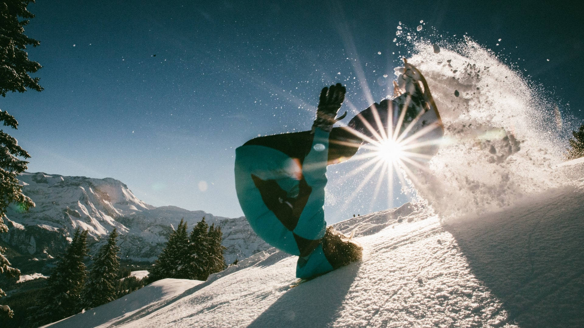 tumbling 桌布 壁紙 — 一名滑雪板運動員在空中，背景是雪山，帶有太陽光鏡頭眩光。