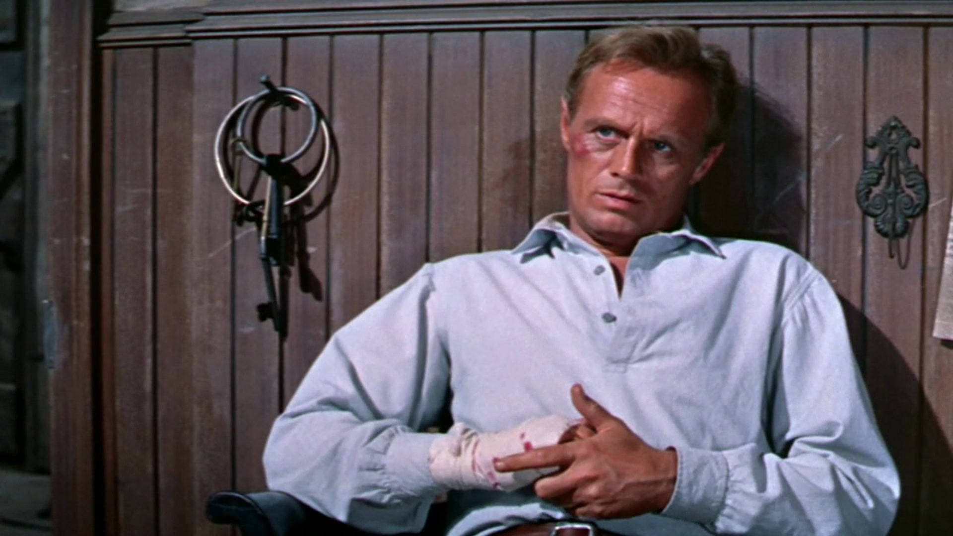 電影動圖 桌布 壁紙 — 一名滿臉鮮血、手纏繃帶的男子，靠著木門，手持鑰匙圈。