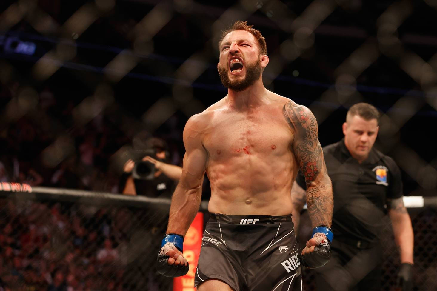 UFC 桌布 壁紙 — 一名滿身刺青的肌肉發達拳手在UFC八角籠中經過艱苦奮戰後勝利咆哮。