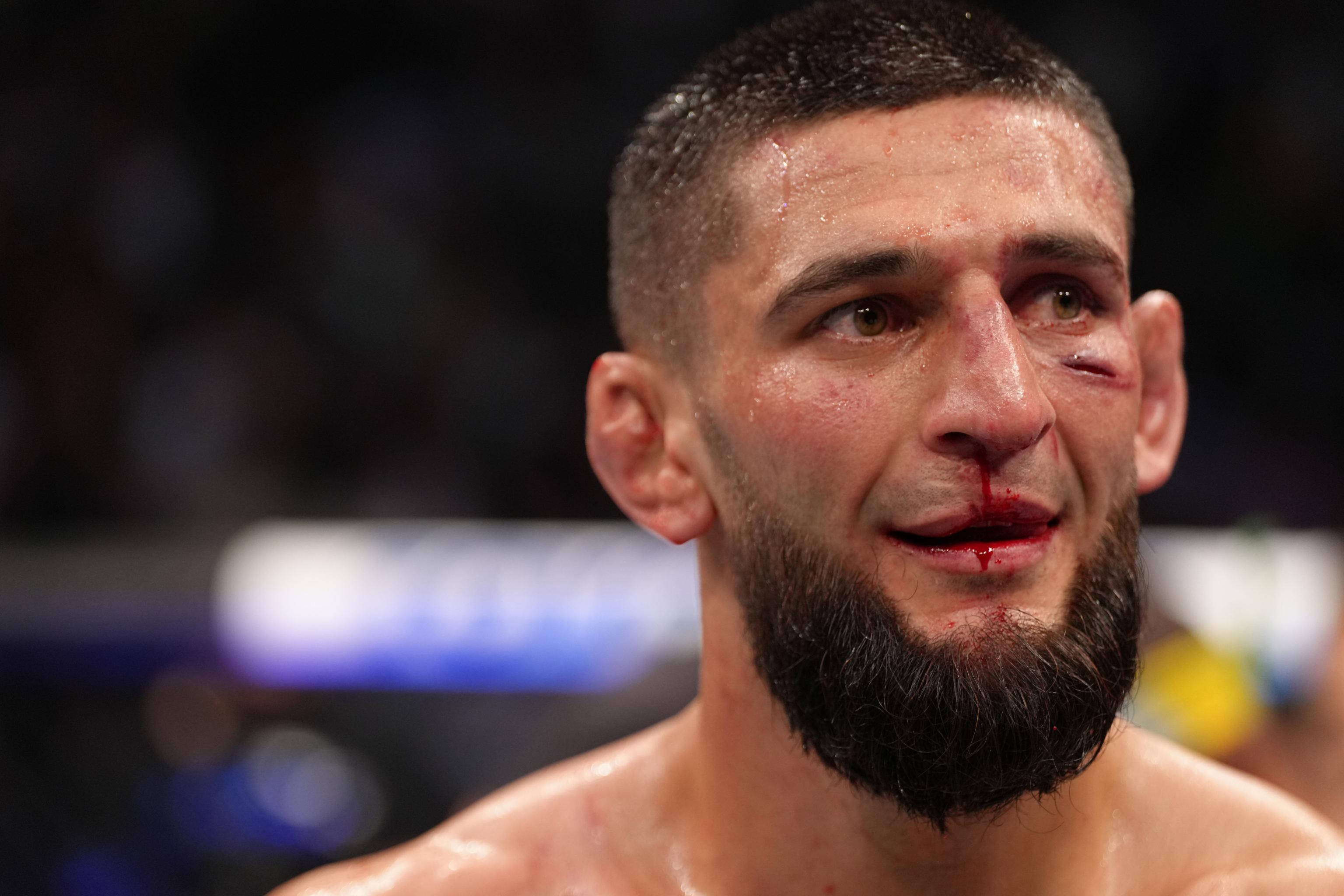 Athletic 桌布 壁紙 — 一名滿身鮮血的UFC拳手，在殘酷比賽後，瘀傷的眼睛和汗水在場館燈光下閃閃發光。