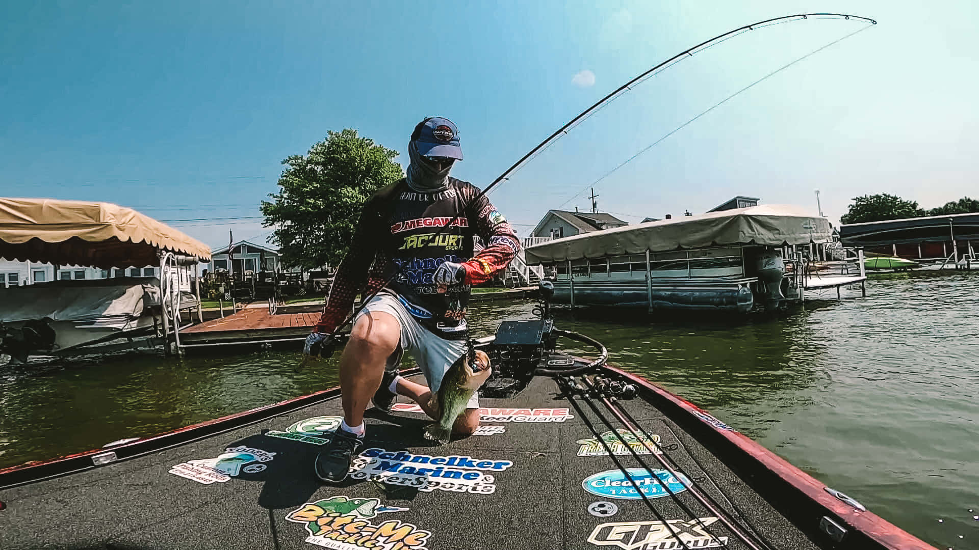 Fishing Bait 桌布 壁紙 — 一名漁夫在船上自豪地拿著一條大鱸魚，同時在陽光明媚的日子裡收線彎曲的釣竿。