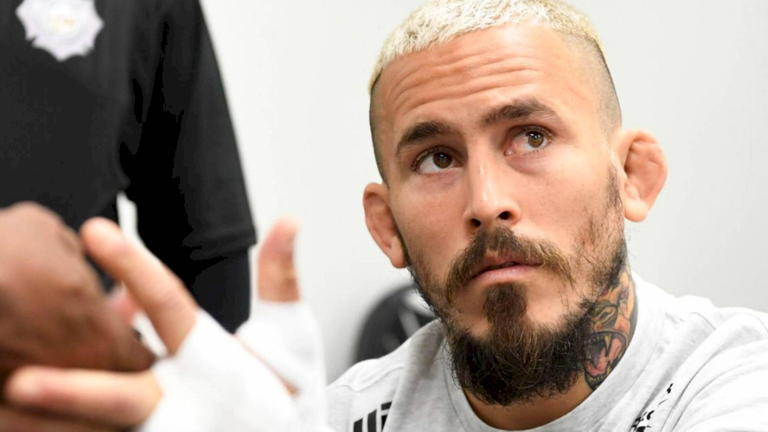 UFC 桌布 壁紙 — 一名漂染頭髮和鬍鬚的男子向上看並用手做手勢的特寫。