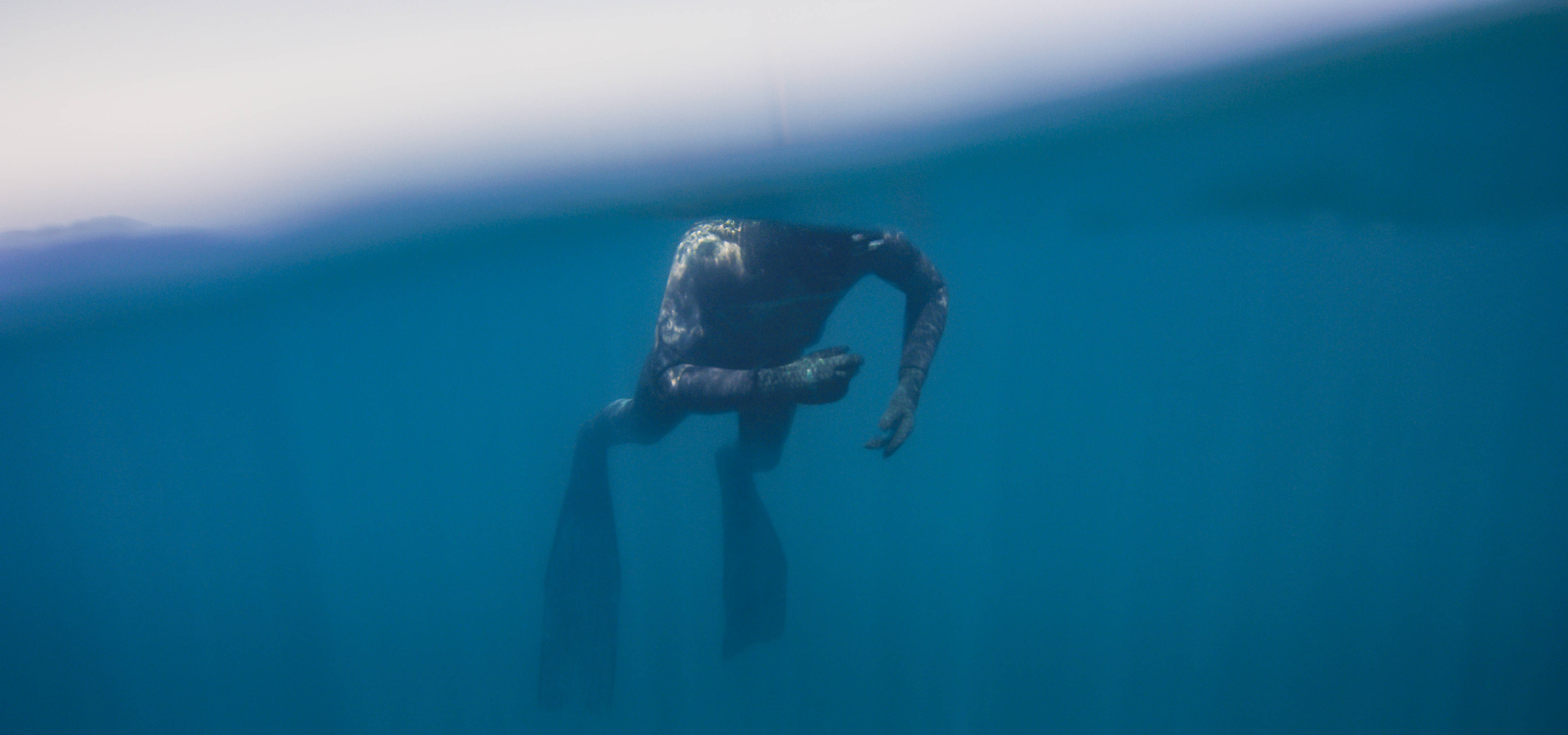 Snorkeling 桌布 壁紙 — 一名潛水員在水中優雅地滑行，腳蹼清晰可見，陽光透過清澈的藍色海面照射下來。