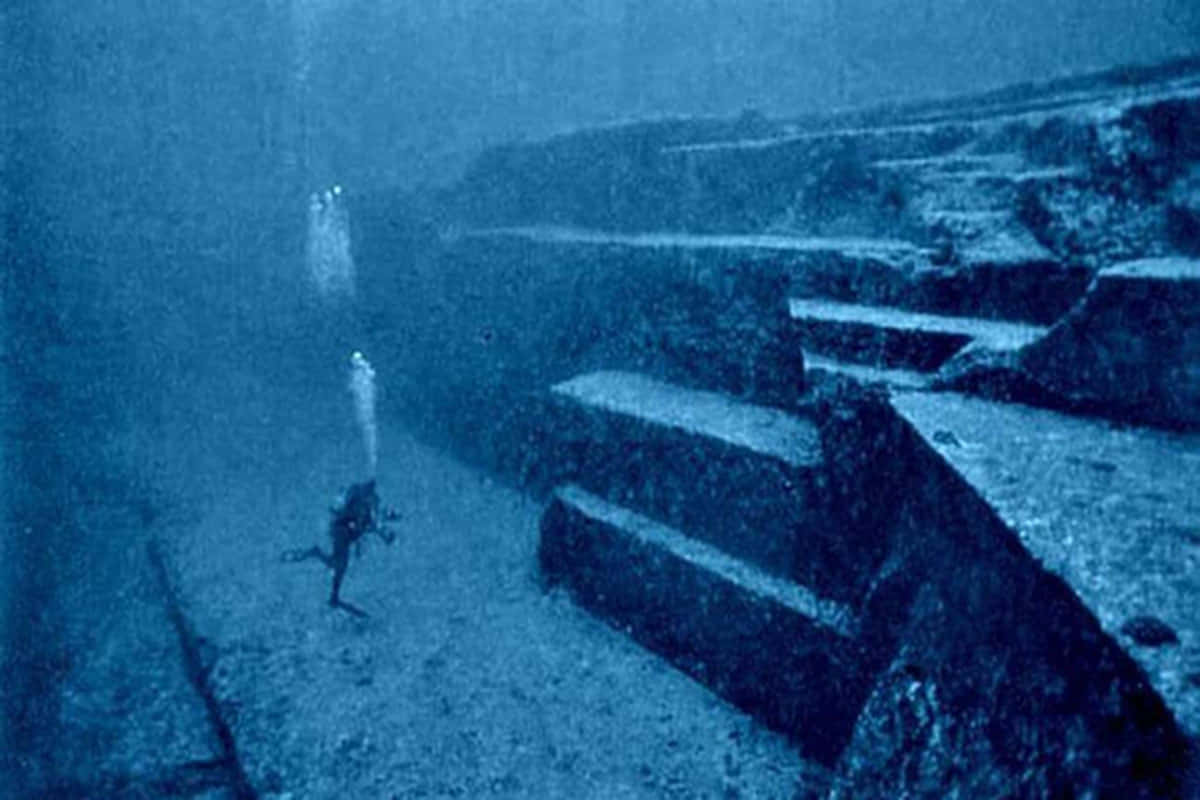 Creepy Ocean 桌布 壁紙 — 一名潛水員在渾濁的藍色水下遺跡中探索古老的 submerged 石階。