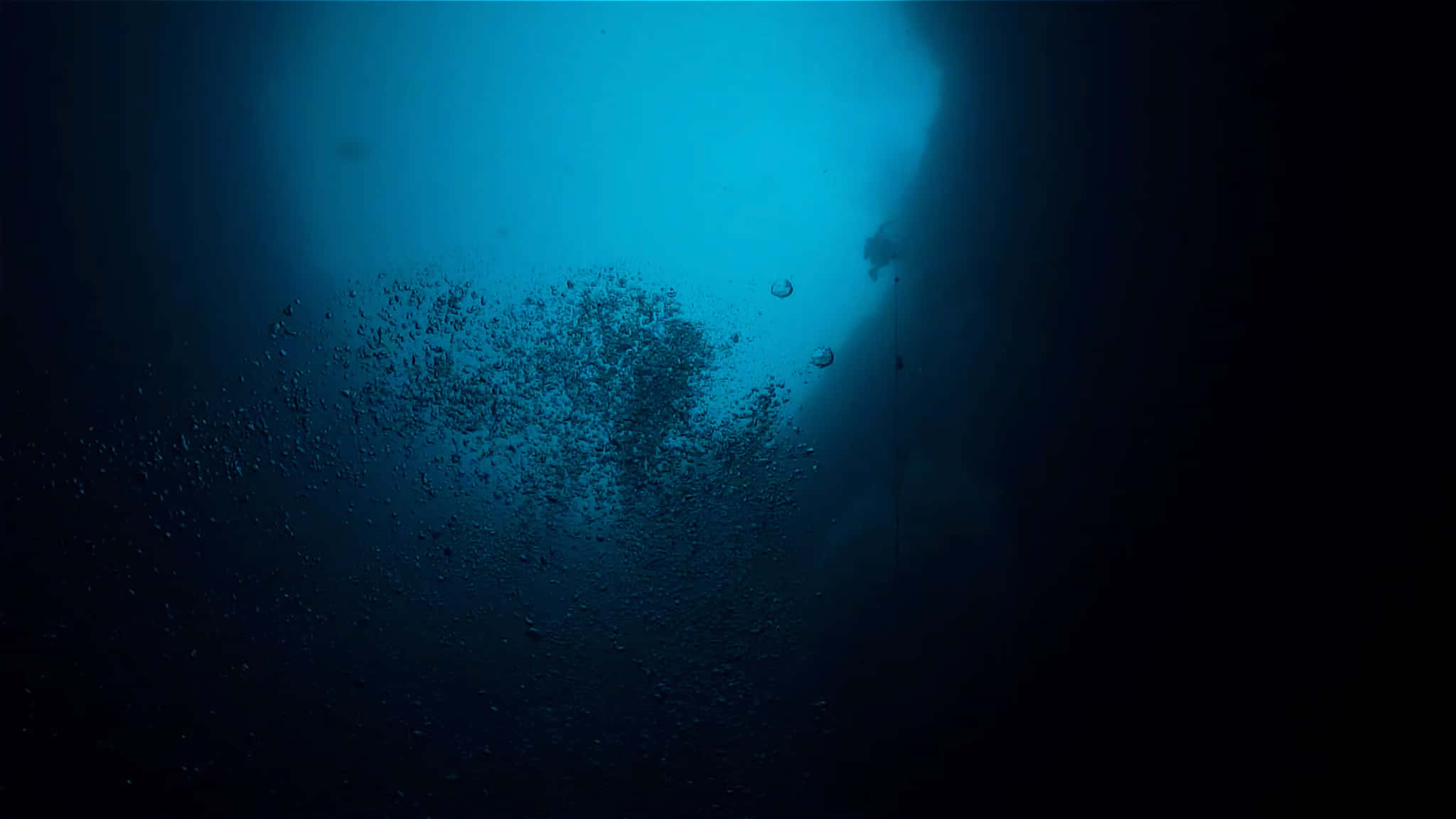 Scary Underwater 桌布 壁紙 — 一名潛水員的剪影穿過碧綠色的海水上升，向著上方明亮的水面釋放氣泡。