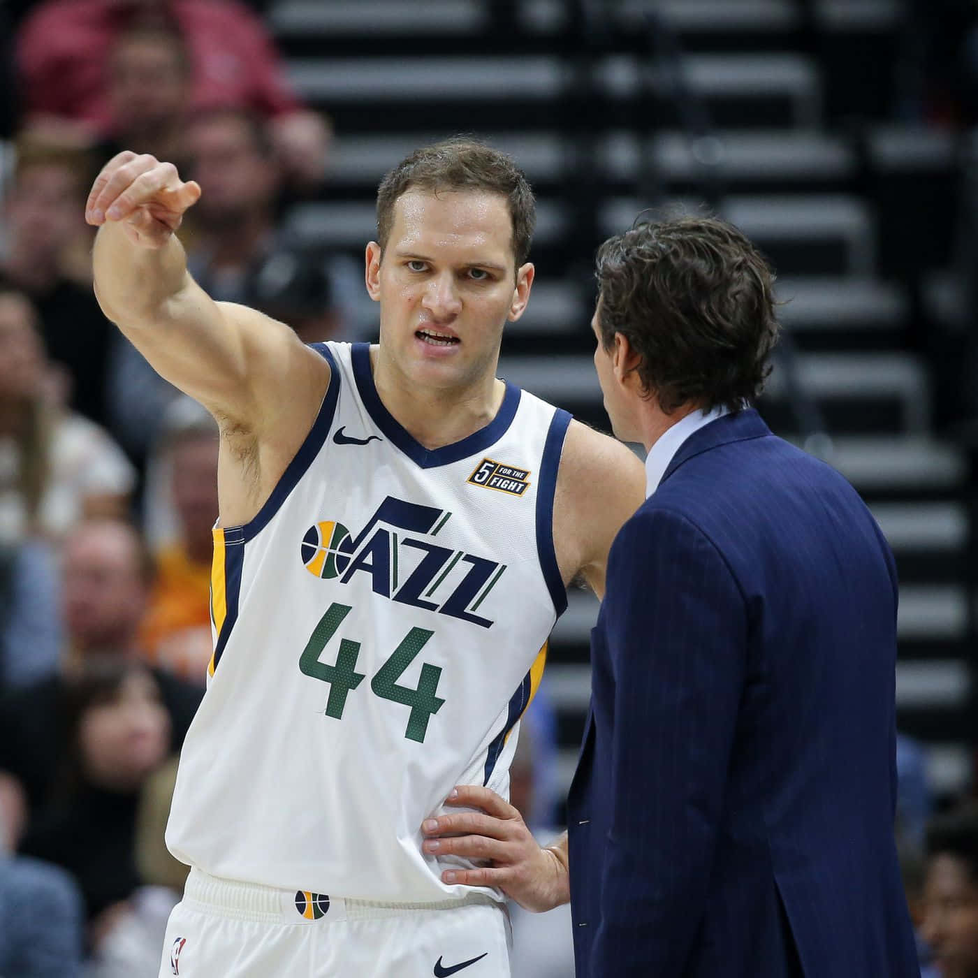 NBA 桌布 壁紙 — 一名猶他爵士籃球運動員身穿白色44號球衣，在比賽中與身穿藍色西裝的教練交談時，做出強調的手勢。