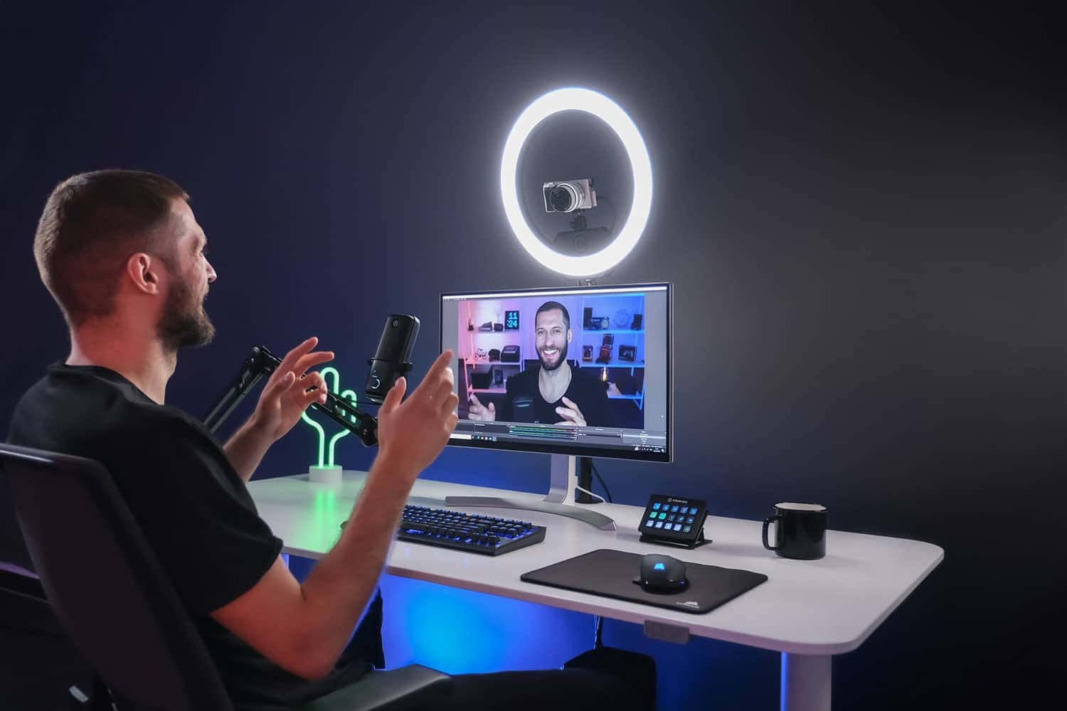Ring Light 桌布 壁紙 — 一名男士在一個時尚的遊戲設置中進行直播，配有發光的環形燈和霓虹燈點綴，背景是深色牆壁。