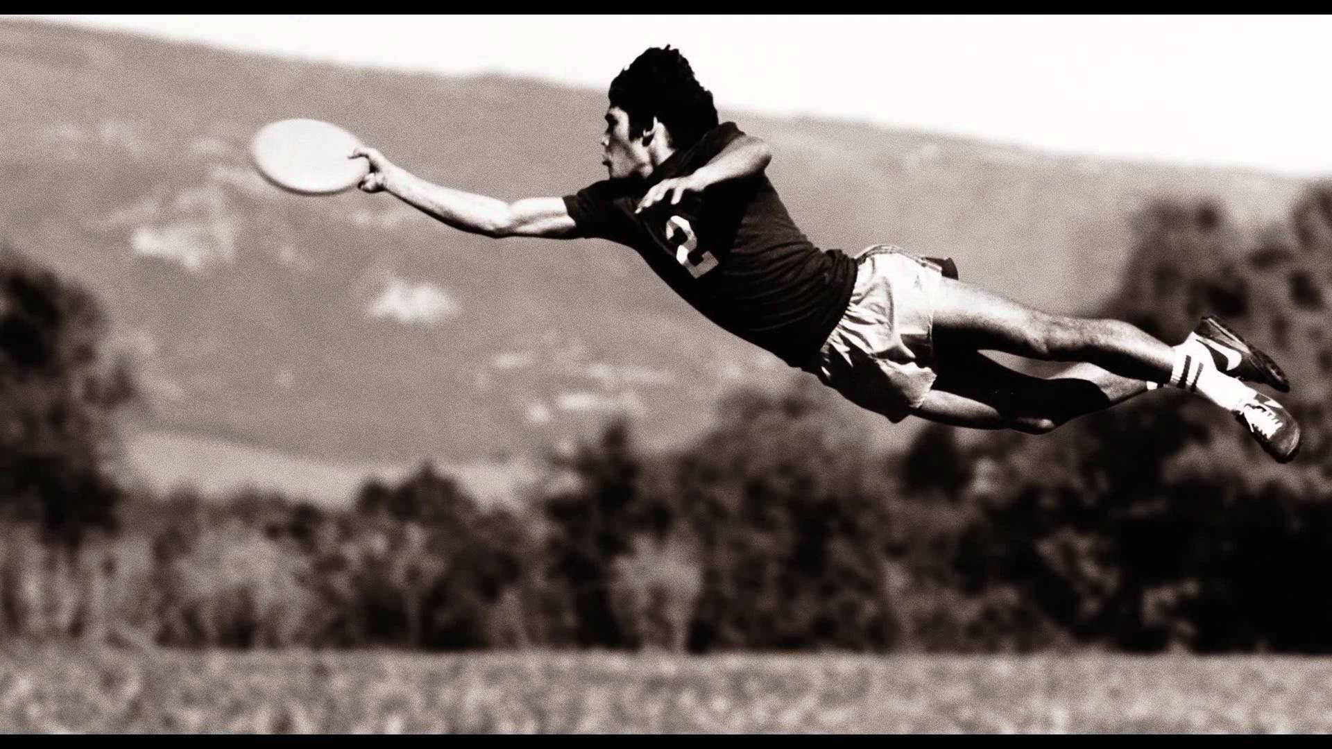 Ultimate Frisbee 桌布 壁紙 — 一名男子以黑白畫面凌空躍起，在朦朧的山景背景下接住飛盤。