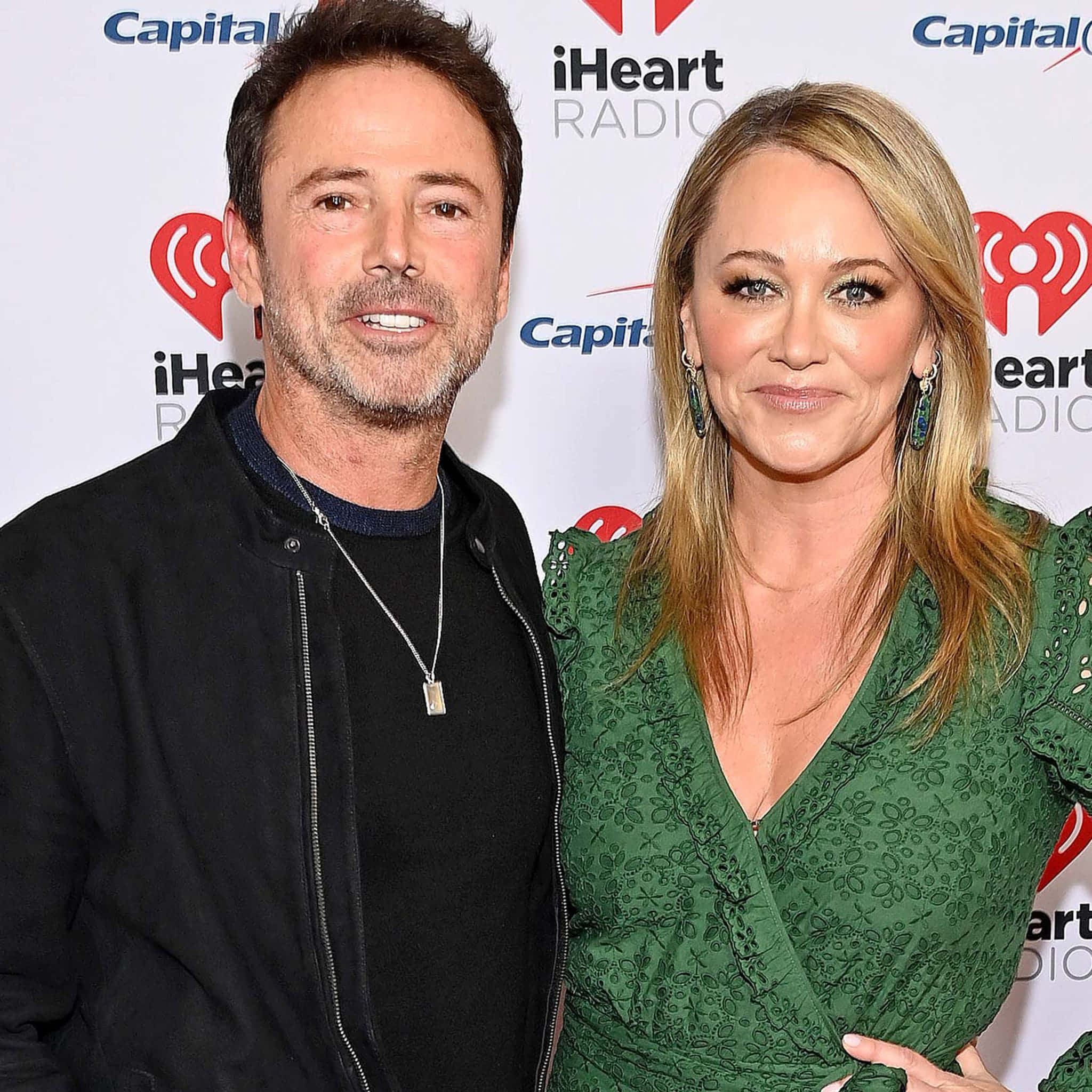 Christine Taylor 桌布 壁紙 — 一名男子和一名女子在Capital iHeartRadio活動中一起擺姿勢，背後有品牌背景。