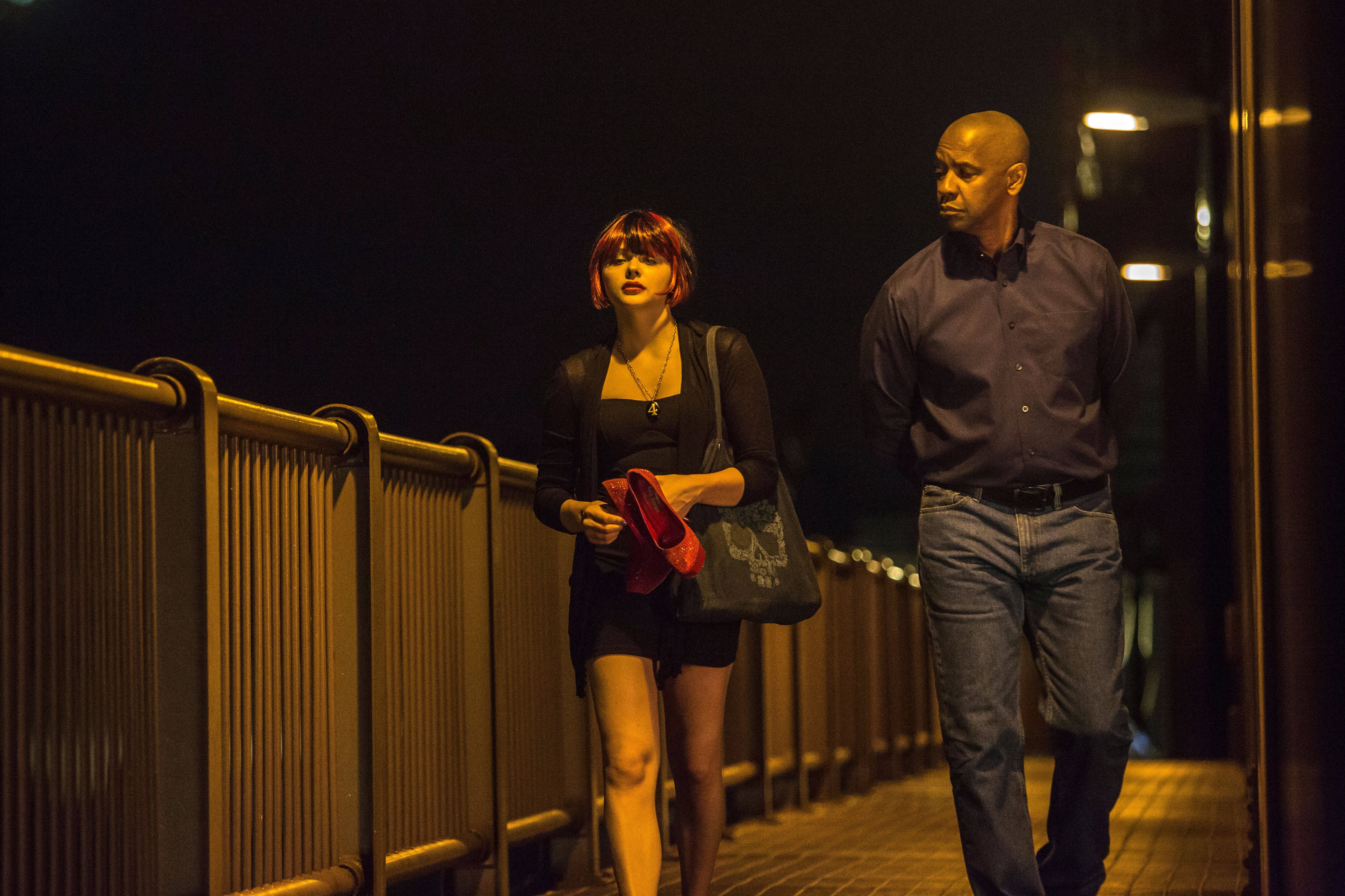 Denzel Washington 桌布 壁紙 — 一名男子和一名女子在夜晚並肩走在溫暖燈光照亮的城市橋樑上，天空漆黑。