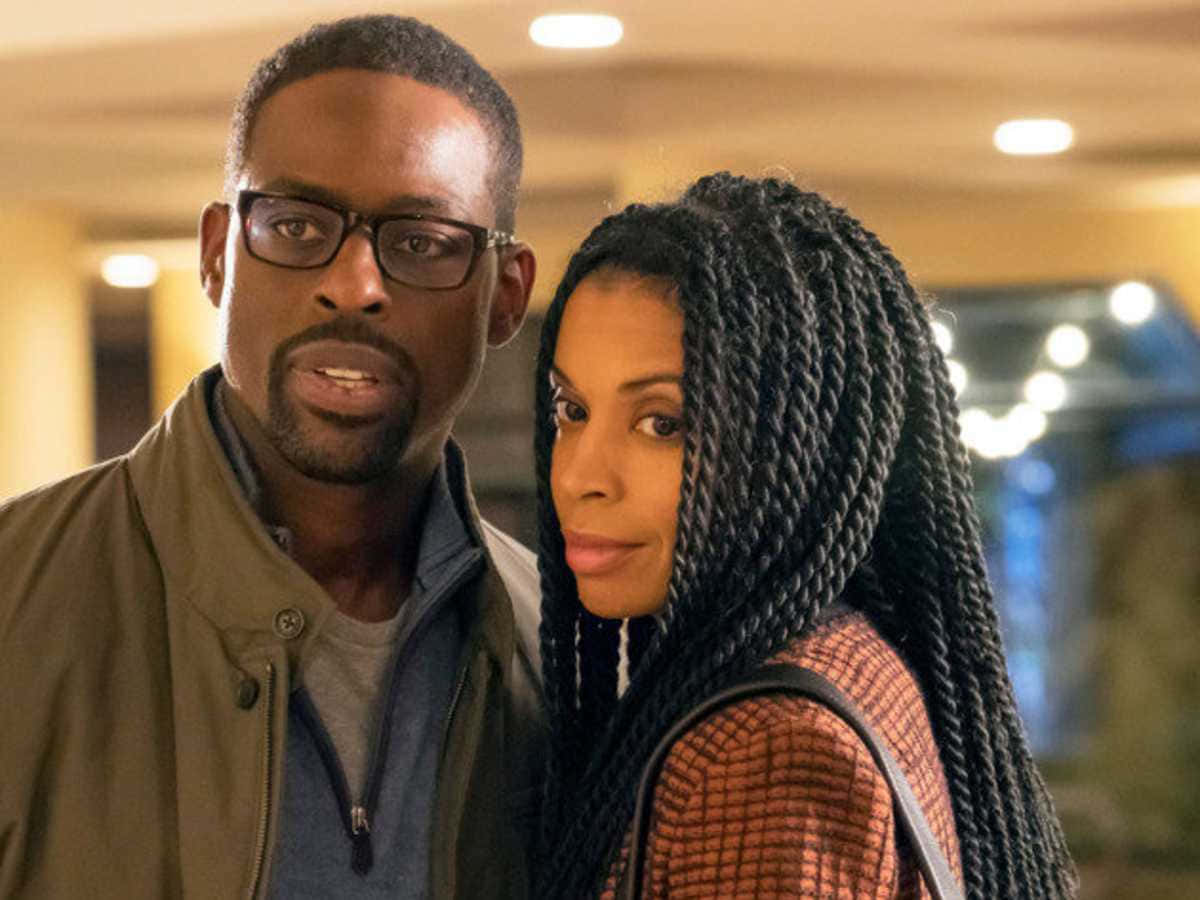 Black Couple 桌布 壁紙 — 一名男子和一名女子在溫暖照明的室內空間中緊密站在一起，兩人都直接看著相機，表情嚴肅。