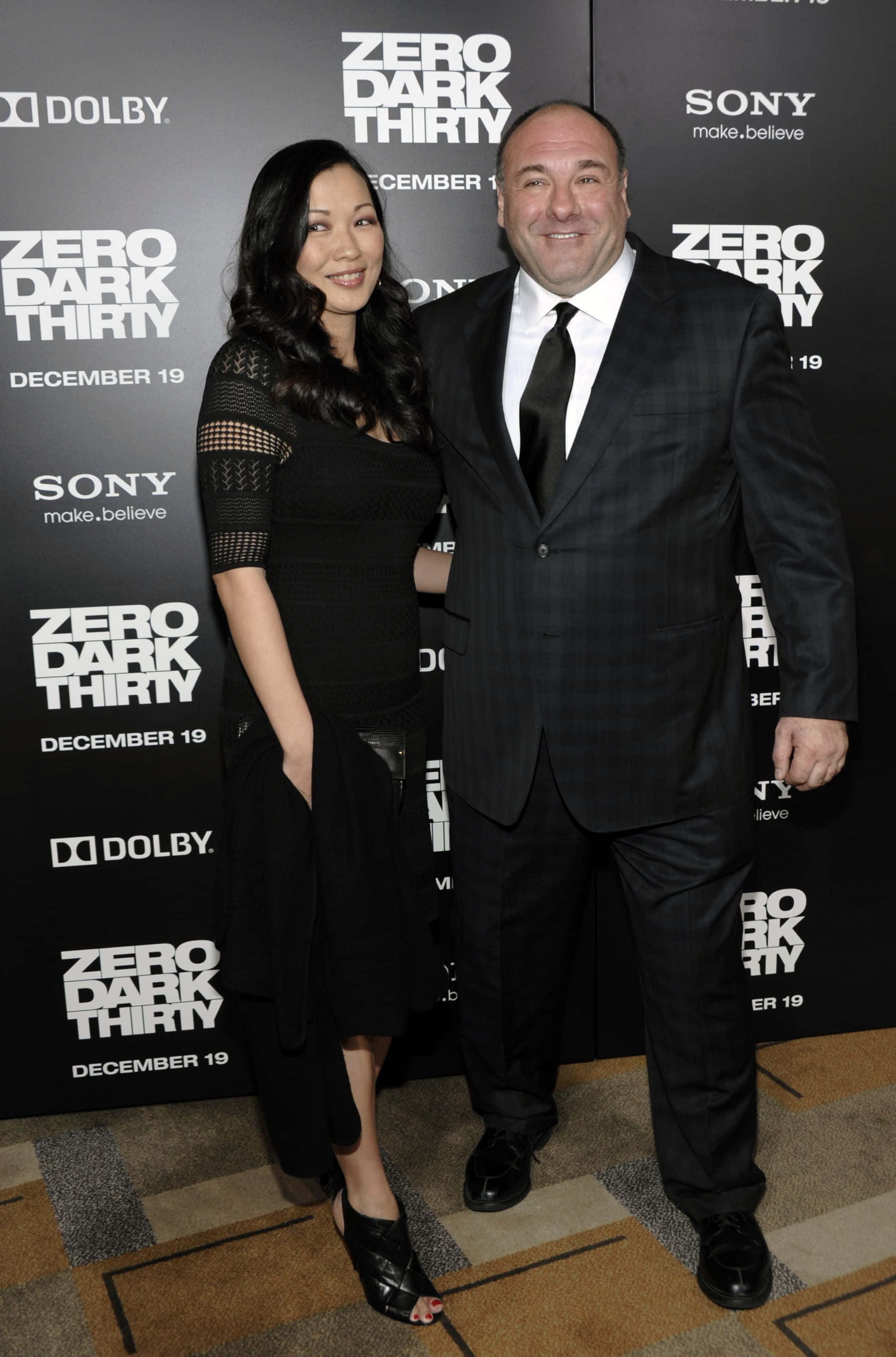James Gandolfini 桌布 壁紙 — 一名男子和一名女子在電影首映會上一起擺姿勢，背後有『Zero Dark Thirty』的品牌標誌。