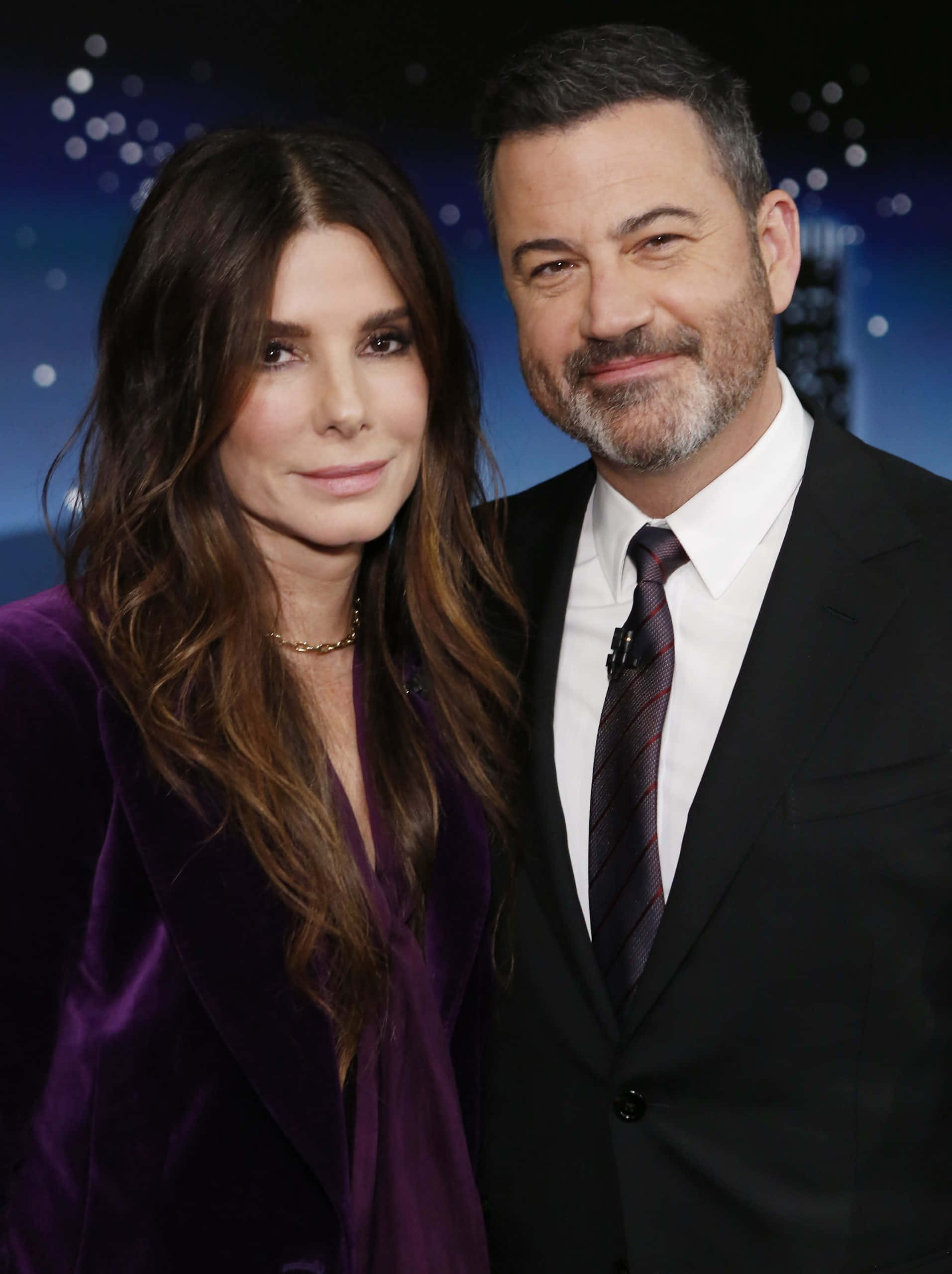 Sandra Bullock 2021 桌布 壁紙 — 一名男子和一名女子穿著正式服裝，在星空夜景和城市燈光背景下合影。