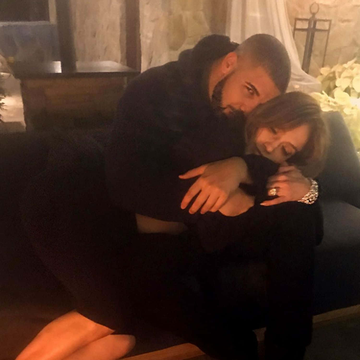 Drake 桌布 壁紙 — 一名男子和女子在溫暖燈光的室內環境中，於沙發上親密擁抱，背景裝飾柔和。