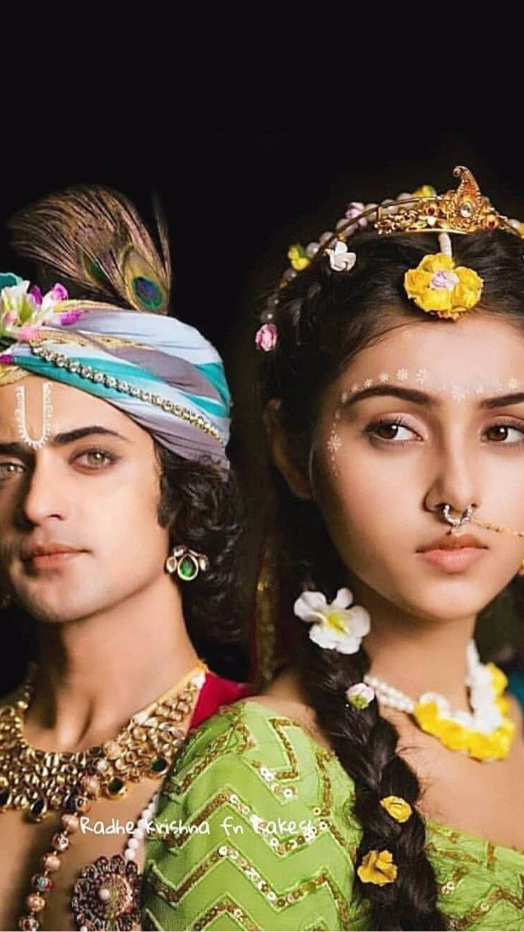 radha krishna serial 桌布 壁紙 — 一名男子和女子穿著華麗的傳統印度服飾，飾有珠寶、孔雀羽毛和鮮花，在深色背景前擺姿勢。