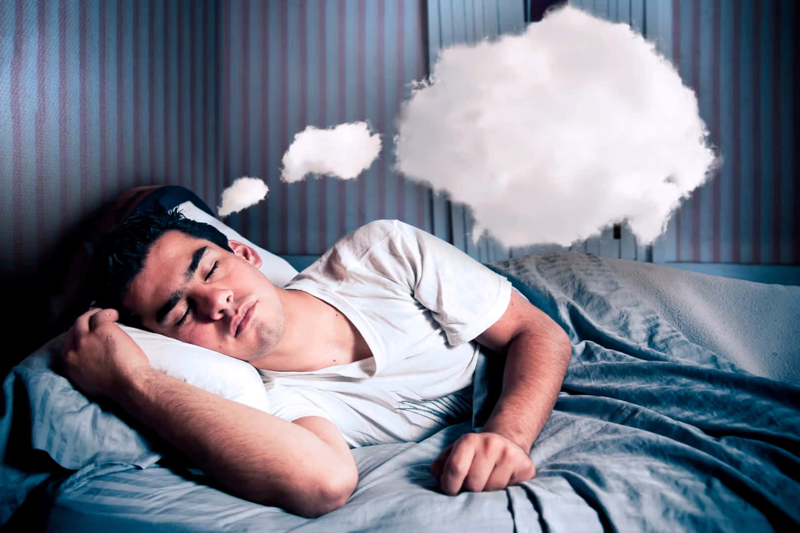 Dreaming 桌布 壁紙 — 一名男子在床上安詳入睡，蓬鬆的白雲像夢境般漂浮在他的頭頂。