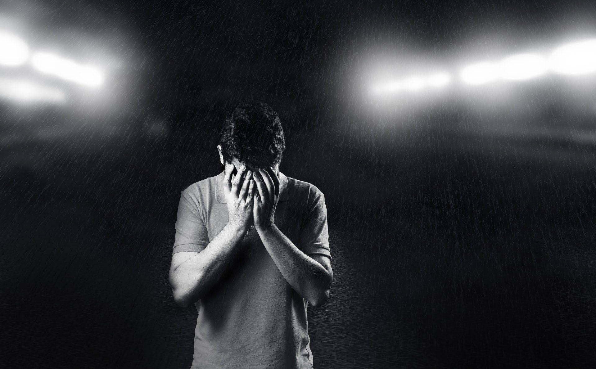 男子在球場燈光下雨中掩面