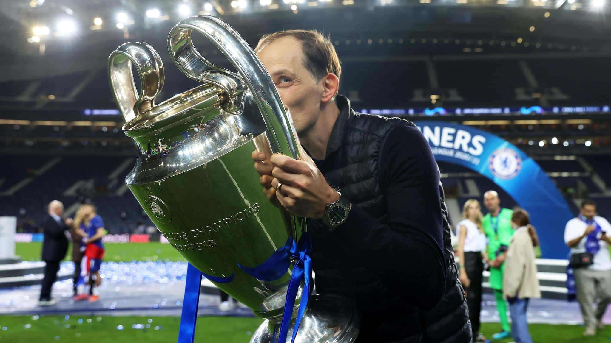 Champions League 桌布 壁紙 — 一名男子在球場燈光下親吻閃閃發光的銀色歐冠獎盃，周圍有紙屑飄落。