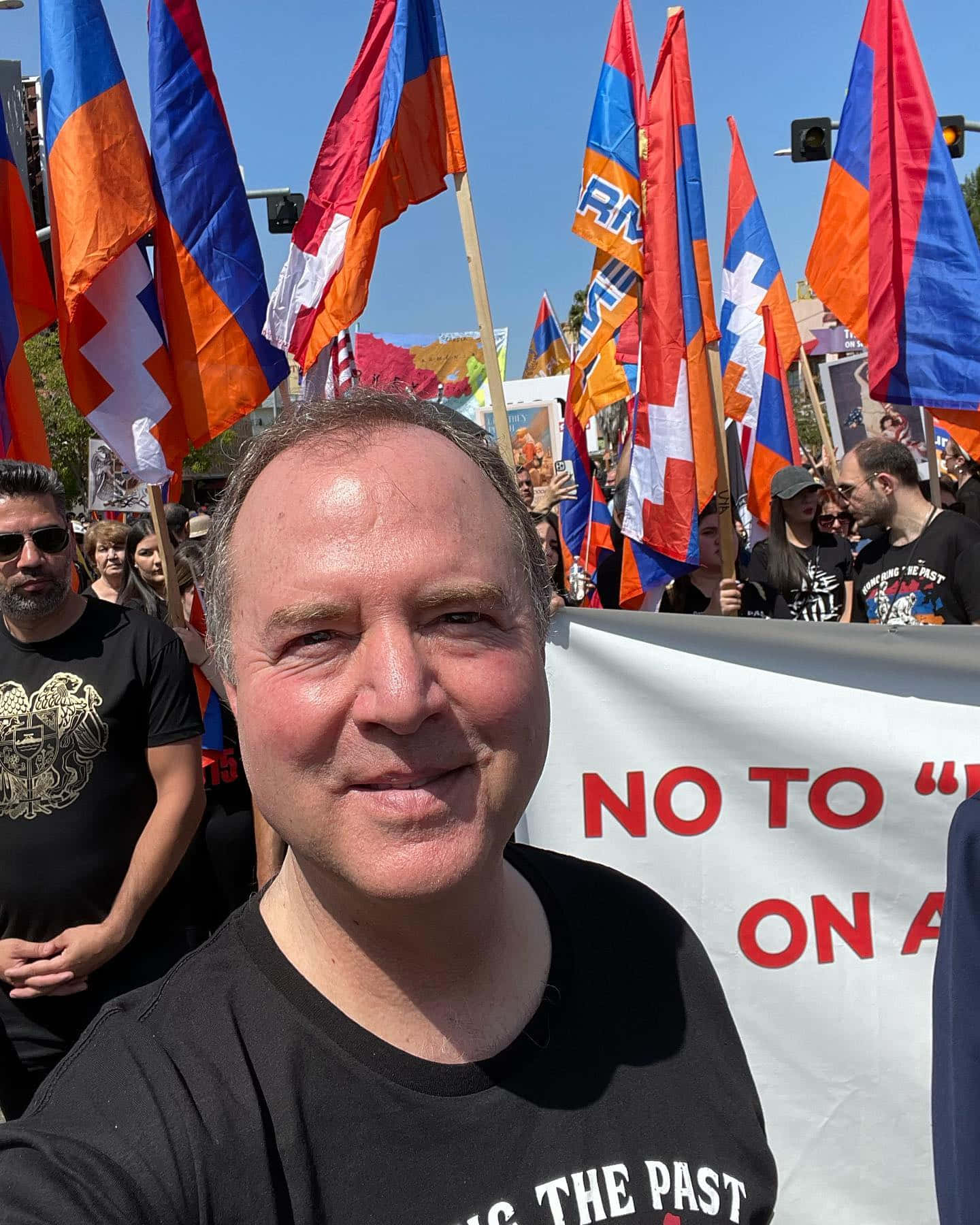 Flag 桌布 壁紙 — 一名男子在白天抗議活動中微笑自拍，背景有揮舞的亞美尼亞國旗和寫著「不」的橫幅。