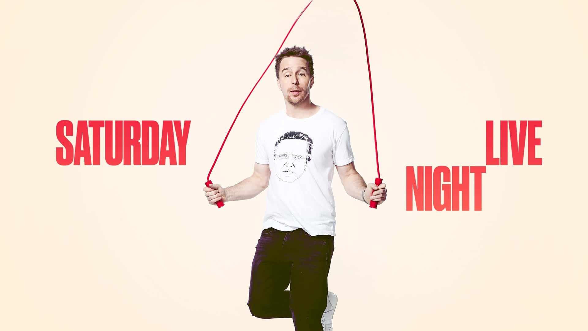 攝影 桌布 壁紙 — 一名男子在米色背景上以紅色粗體「SATURDAY NIGHT LIVE」文字跳紅色跳繩的中途動作。