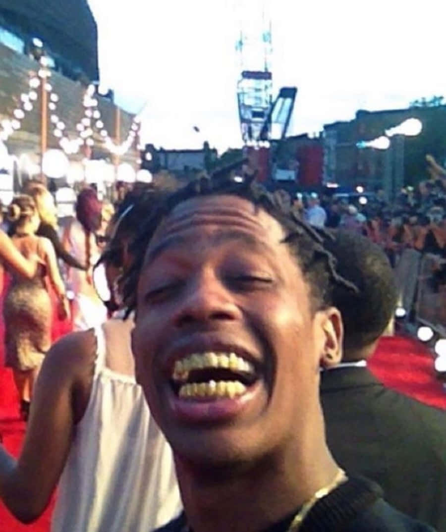 Travis Scott Funny 桌布 壁紙 — 一名男子在紅地毯上開懷大笑，身後有明亮的燈光和人群。