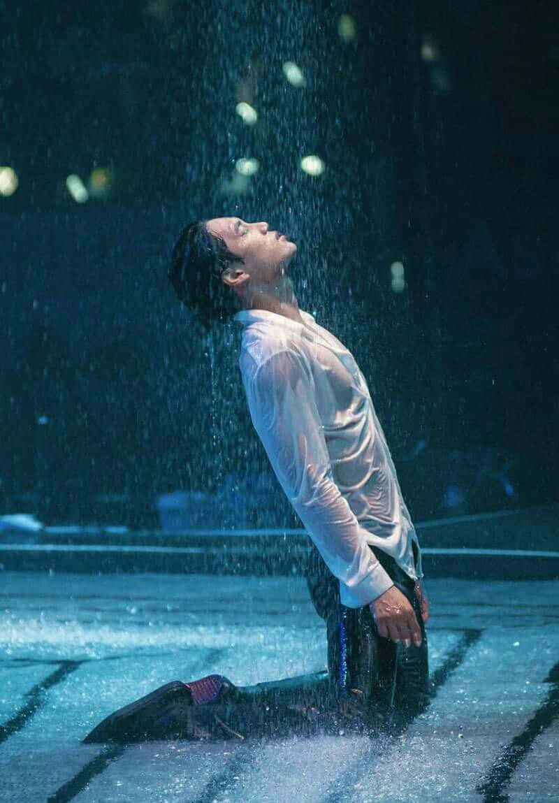 emotion 桌布 壁紙 — 一名男子在藍色舞台燈光下跪在雨中，水從他濕透的白襯衫上滴落。