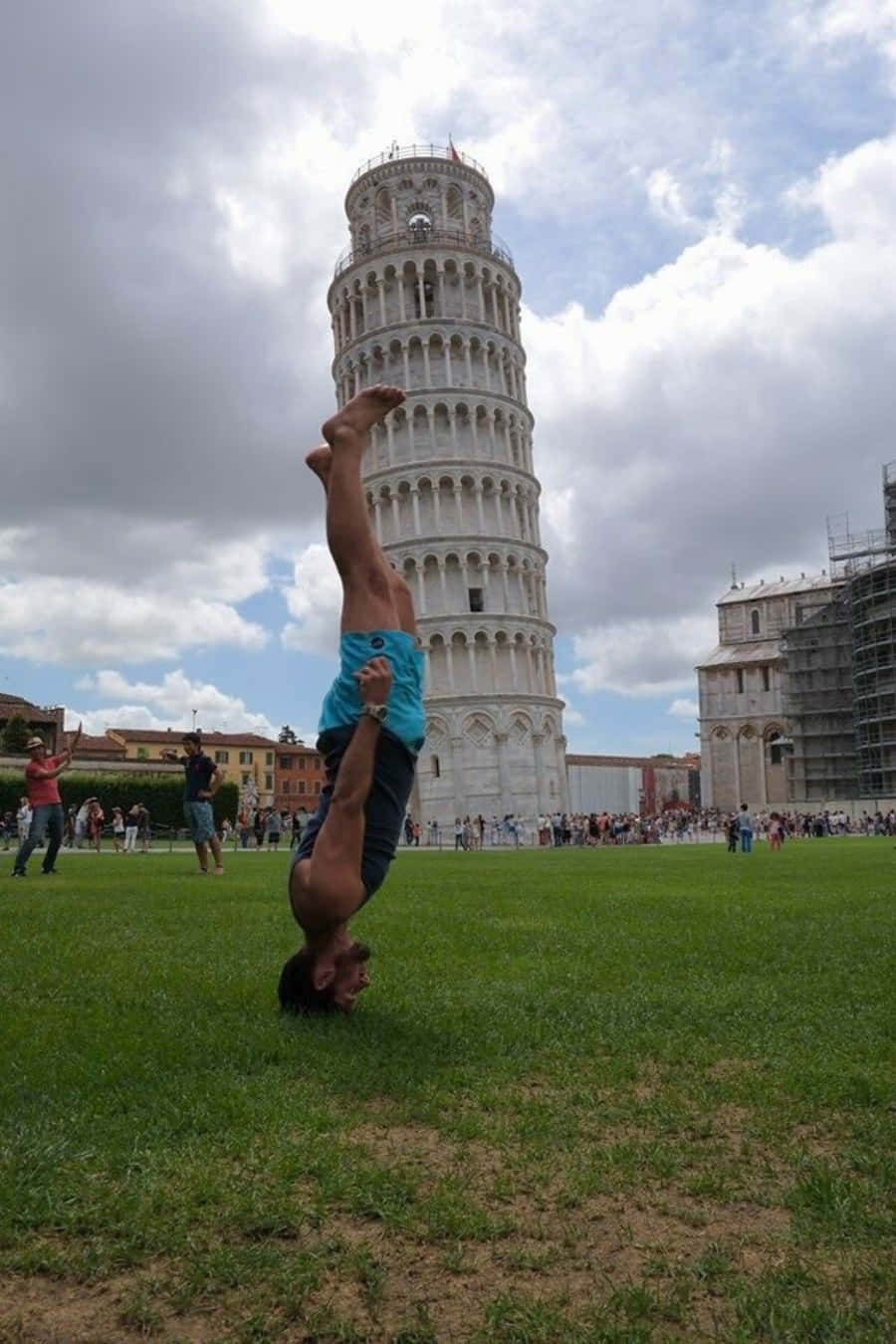 Pisa 桌布 壁紙 — 一名男子在陰天下於標誌性斜塔前的草地上表演倒立。