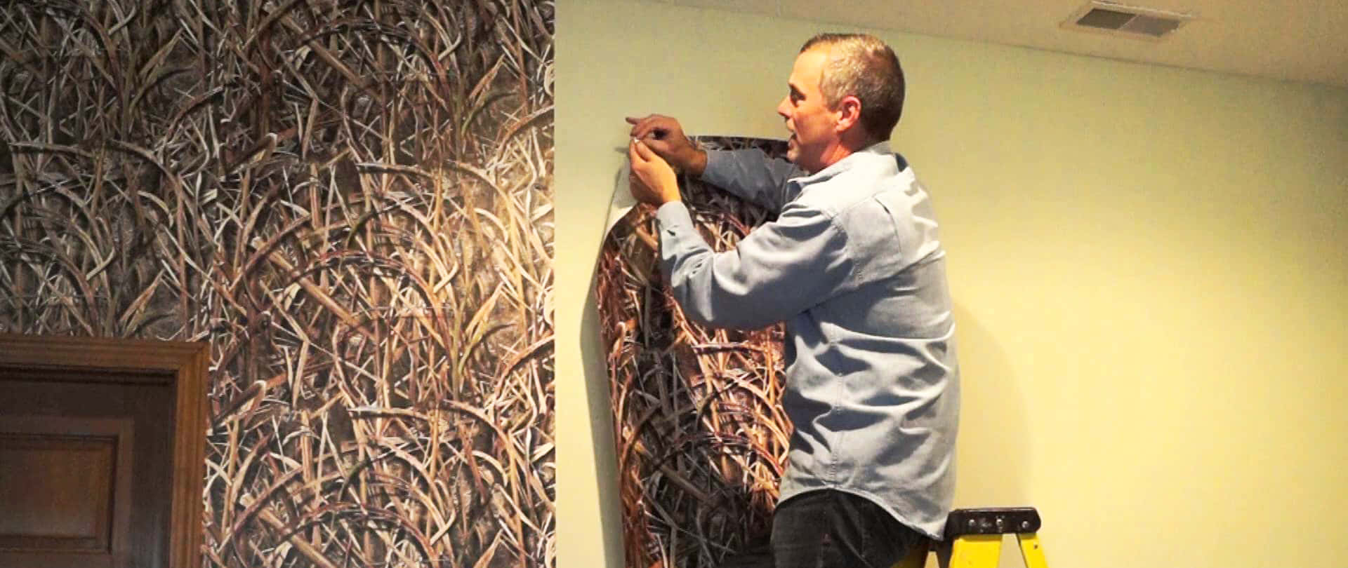Installation Art 桌布 壁紙 — 一名男子在黃色梯子上，將迷彩圖案壁紙貼在木門框旁邊的淺色牆上。
