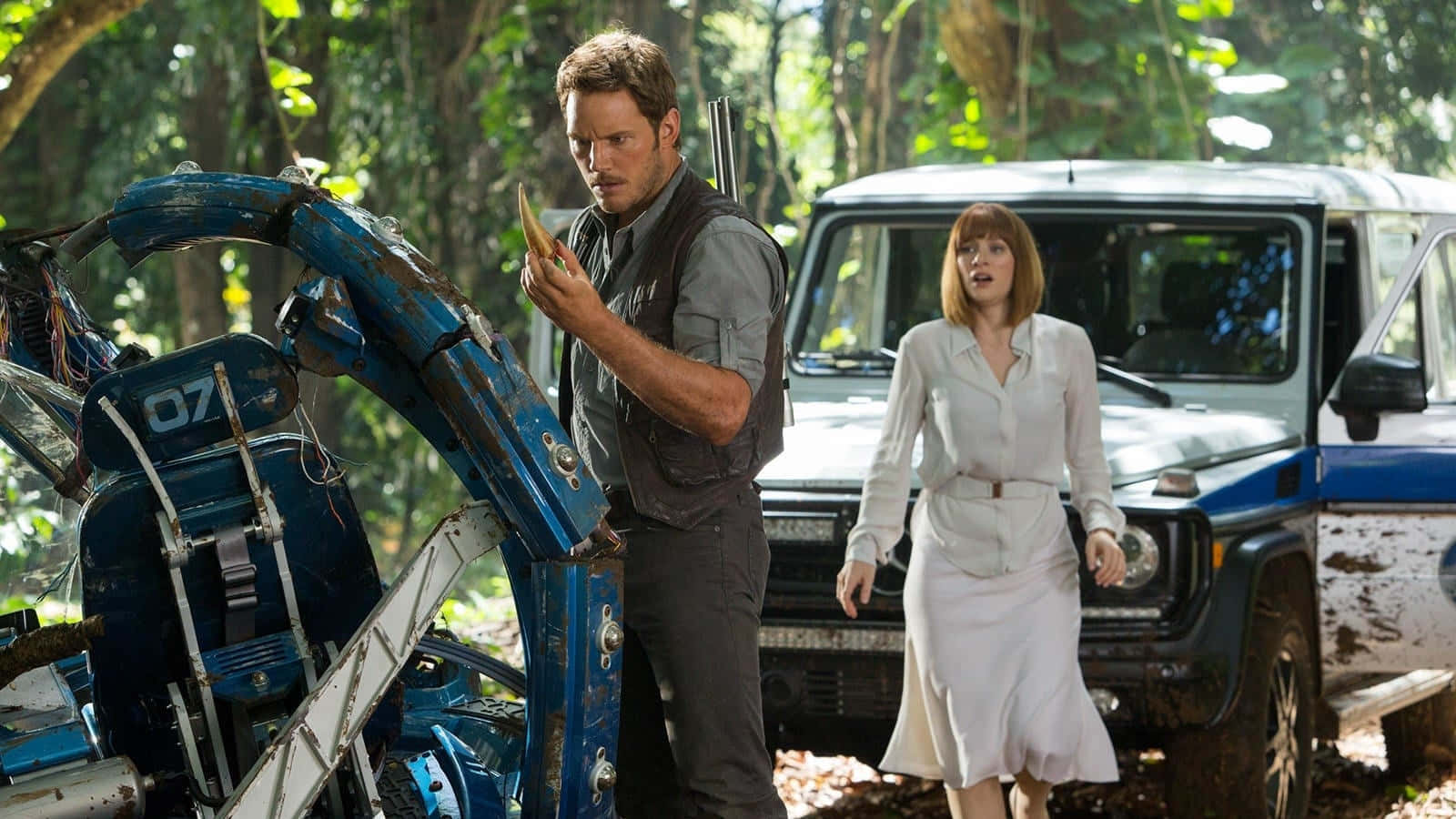 Jurassic World 桌布 壁紙 — 一名男子檢查一輛損壞的藍色車輛，而一名白衣女子則沿著一輛白色吉普車穿過茂密的綠色叢林。