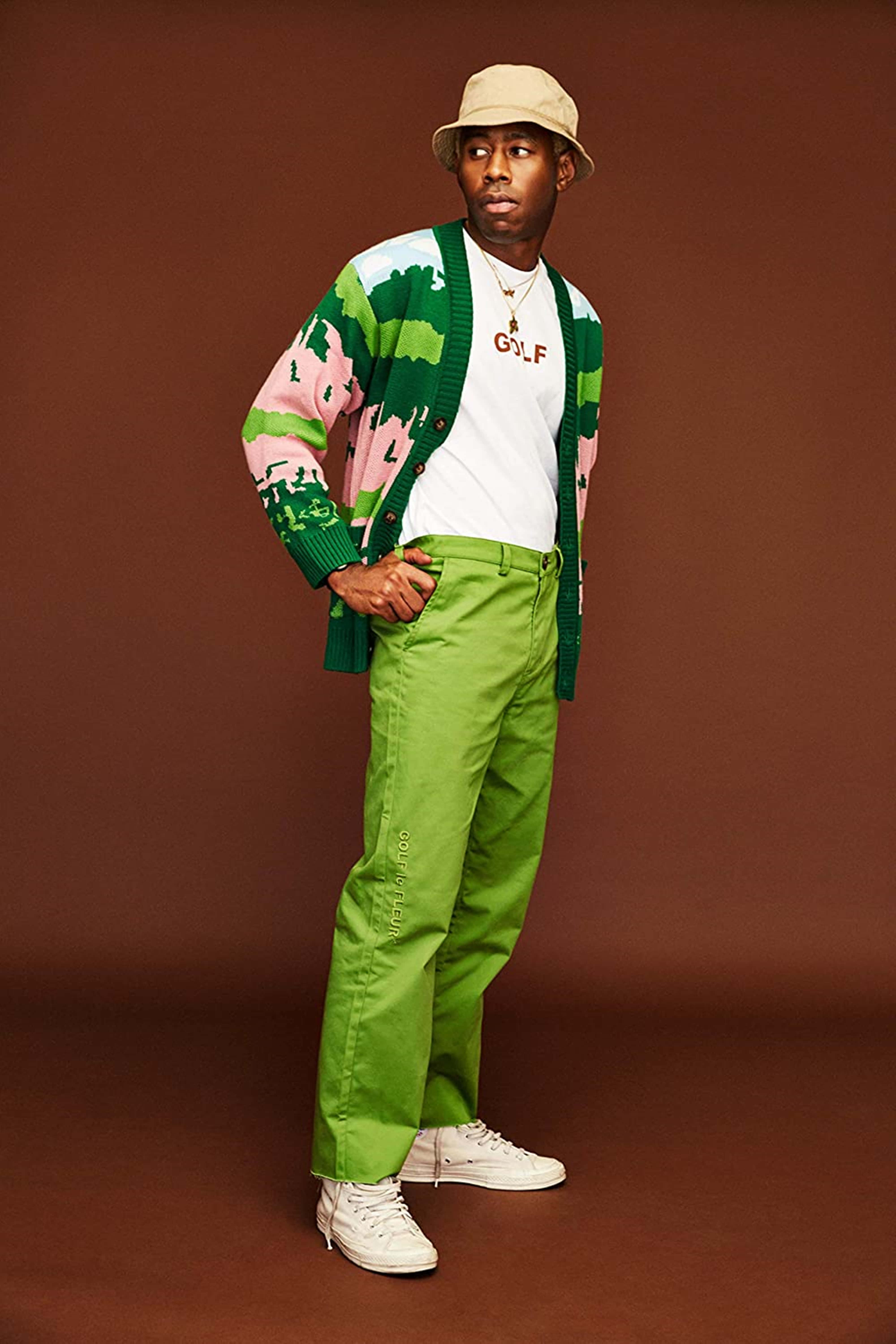 Tyler The Creator 4K 桌布 壁紙 — 一名男子穿著鮮豔的綠色和粉紅色圖案開襟衫、白色T恤和亮綠色褲子，在純棕色攝影棚背景前自信地擺姿勢。