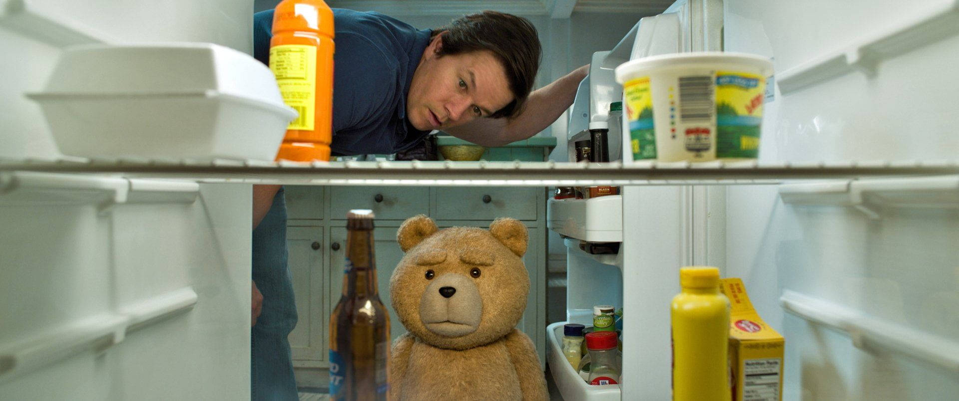 Ted 桌布 壁紙 — 一名男子窺視冰箱內部，一隻泰迪熊直立於調味品和食物之間。