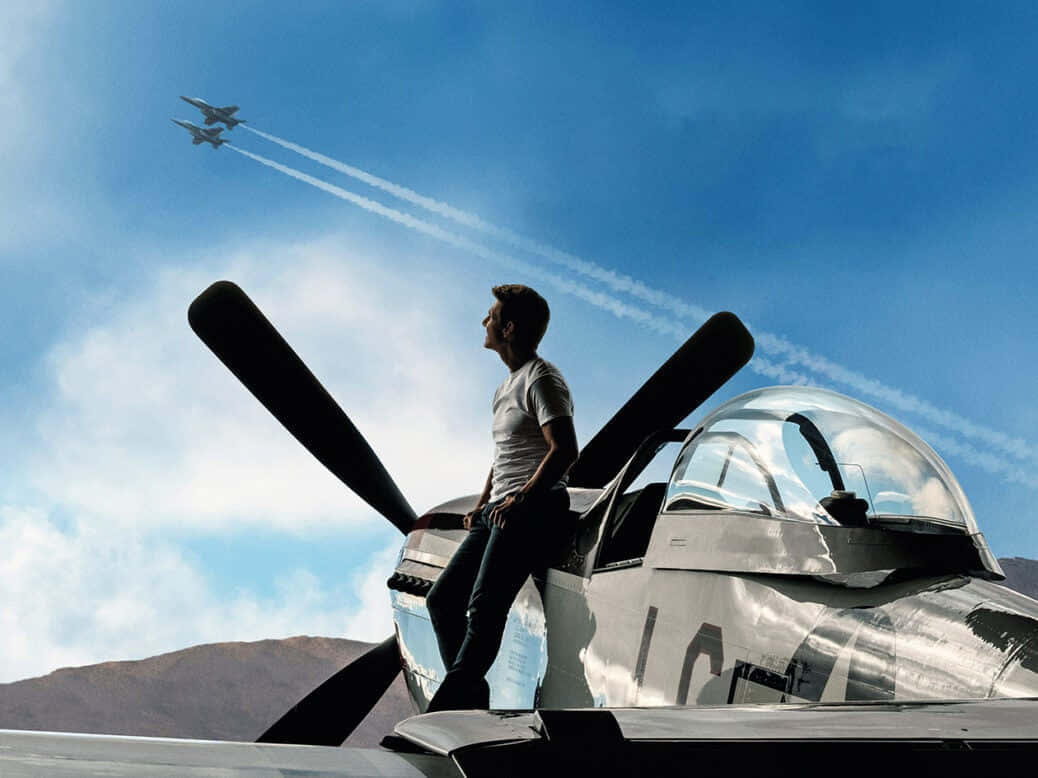 Plane 桌布 壁紙 — 一名男子站在一架復古螺旋槳飛機頂部向上仰望，兩架噴射機劃過明亮的藍天，留下白色凝結尾跡。