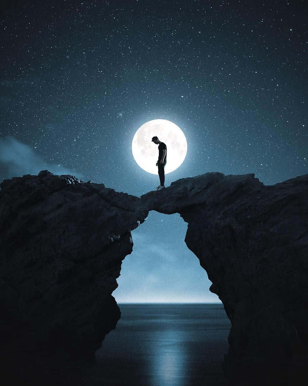 一名男子站在夜空中的岩石上 壁紙