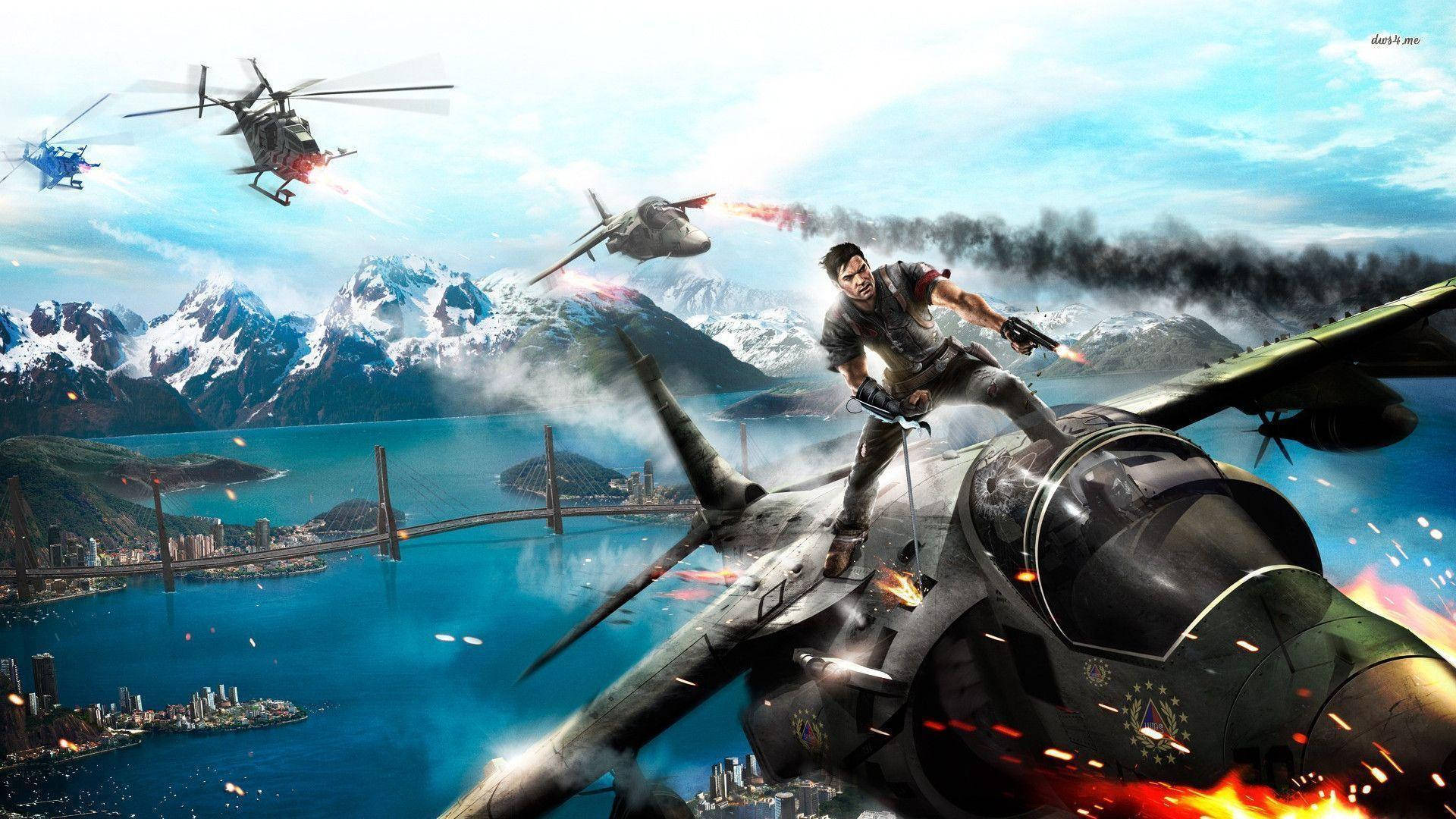 just cause 2 桌布 壁紙 — 一名男子緊抓著一架燃燒的戰鬥機，直升機和爆炸在沿海城市上空肆虐，背景是白雪覆蓋的山脈。