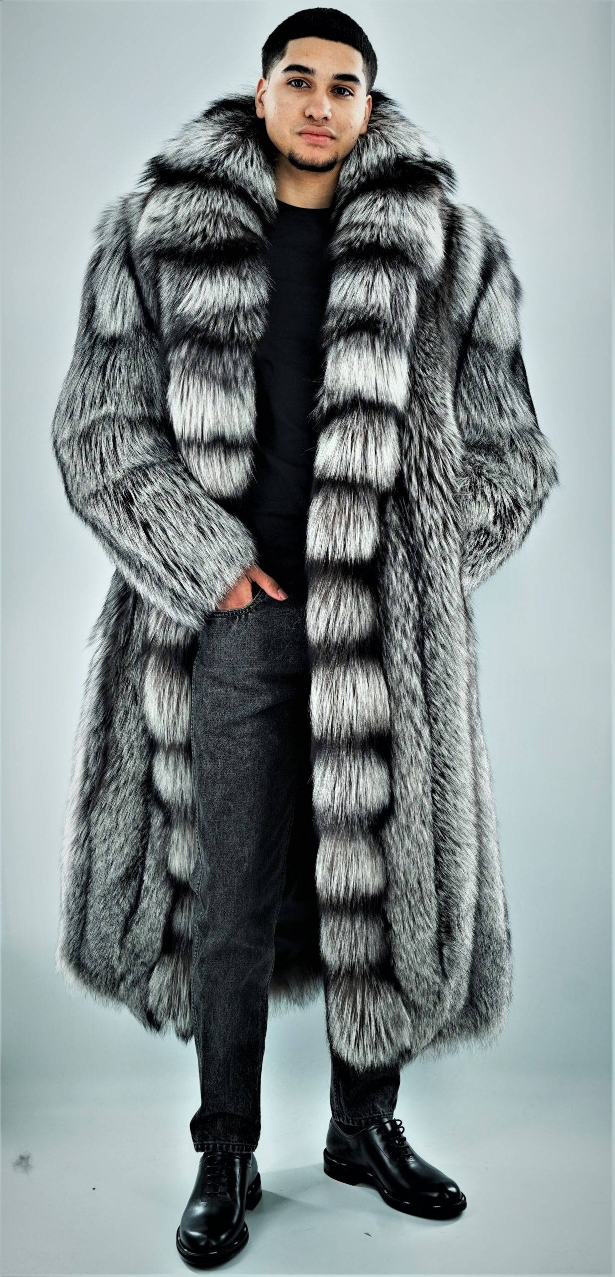 fur 桌布 壁紙 — 一名男子自信地穿著一件長款銀灰色毛皮大衣，帶有蓬鬆的領子，背景是純灰色攝影棚。