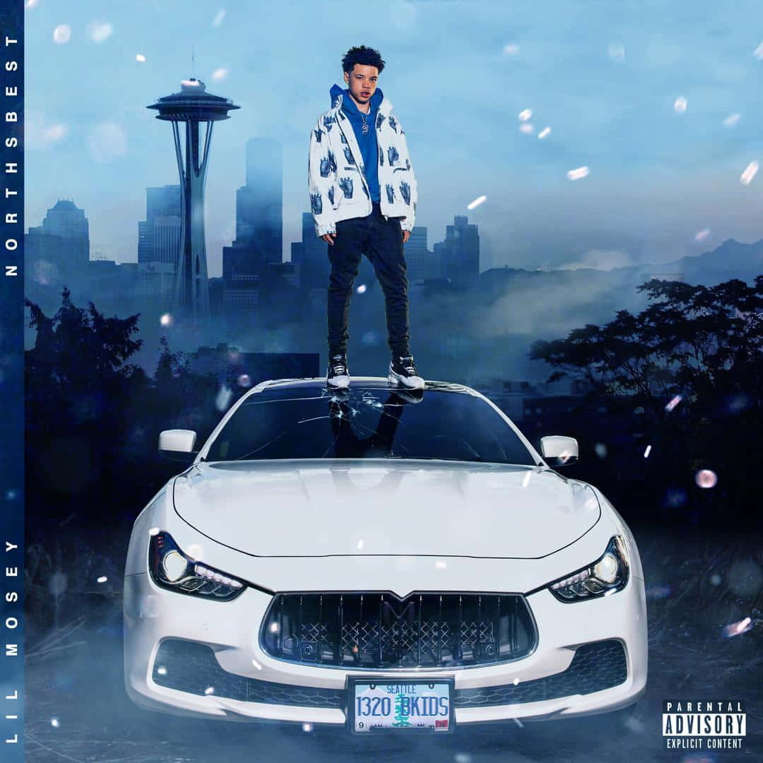 Lil Mosey 桌布 壁紙 — 一名男子自信地站在白色跑車上，背景是霧氣瀰漫的西雅圖天際線，包括太空針塔。