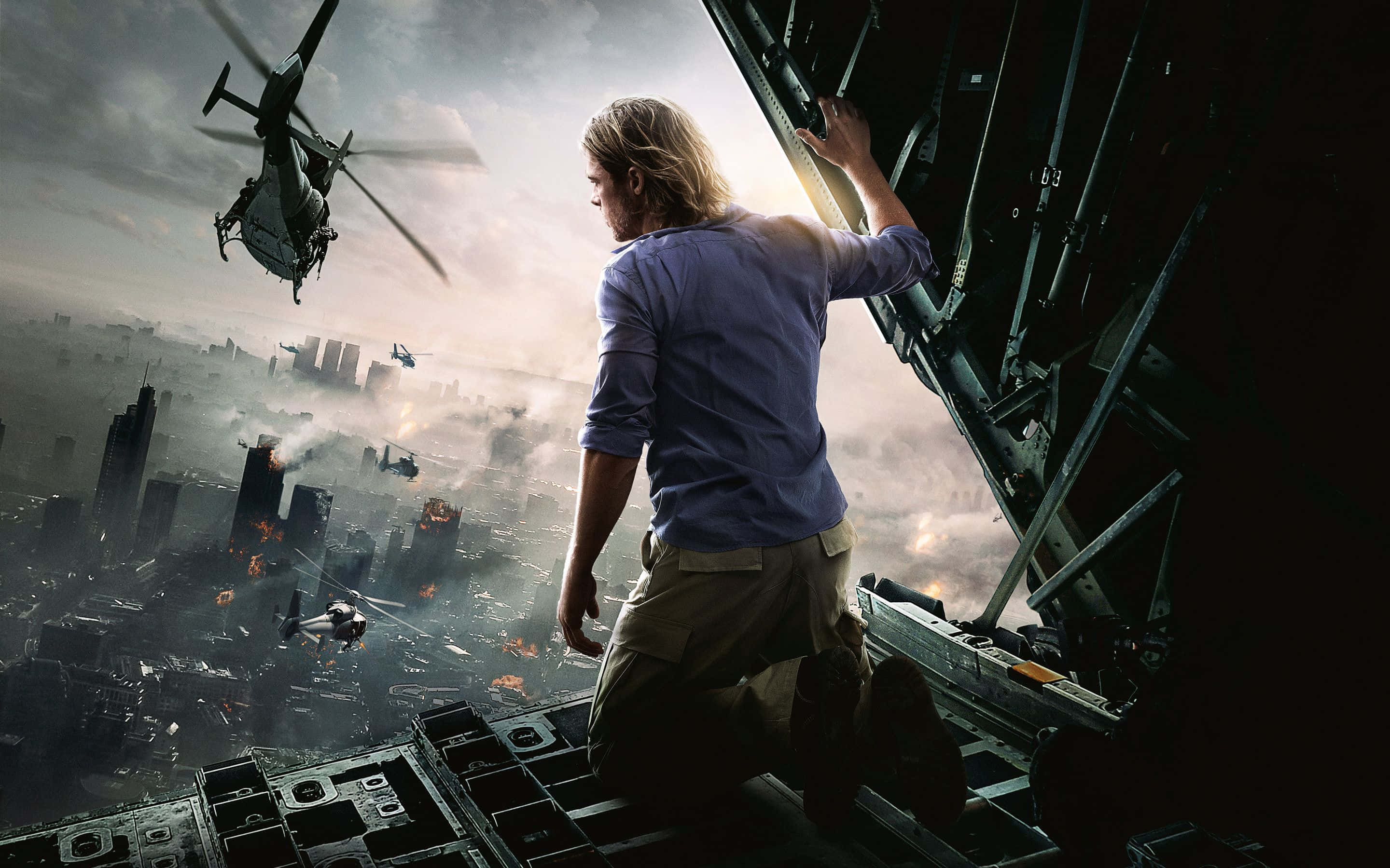 Action Movie 桌布 壁紙 — 一名男子跪在戰機邊緣，俯瞰著燃燒的城市，直升機在煙霧瀰漫的天空中飛行。