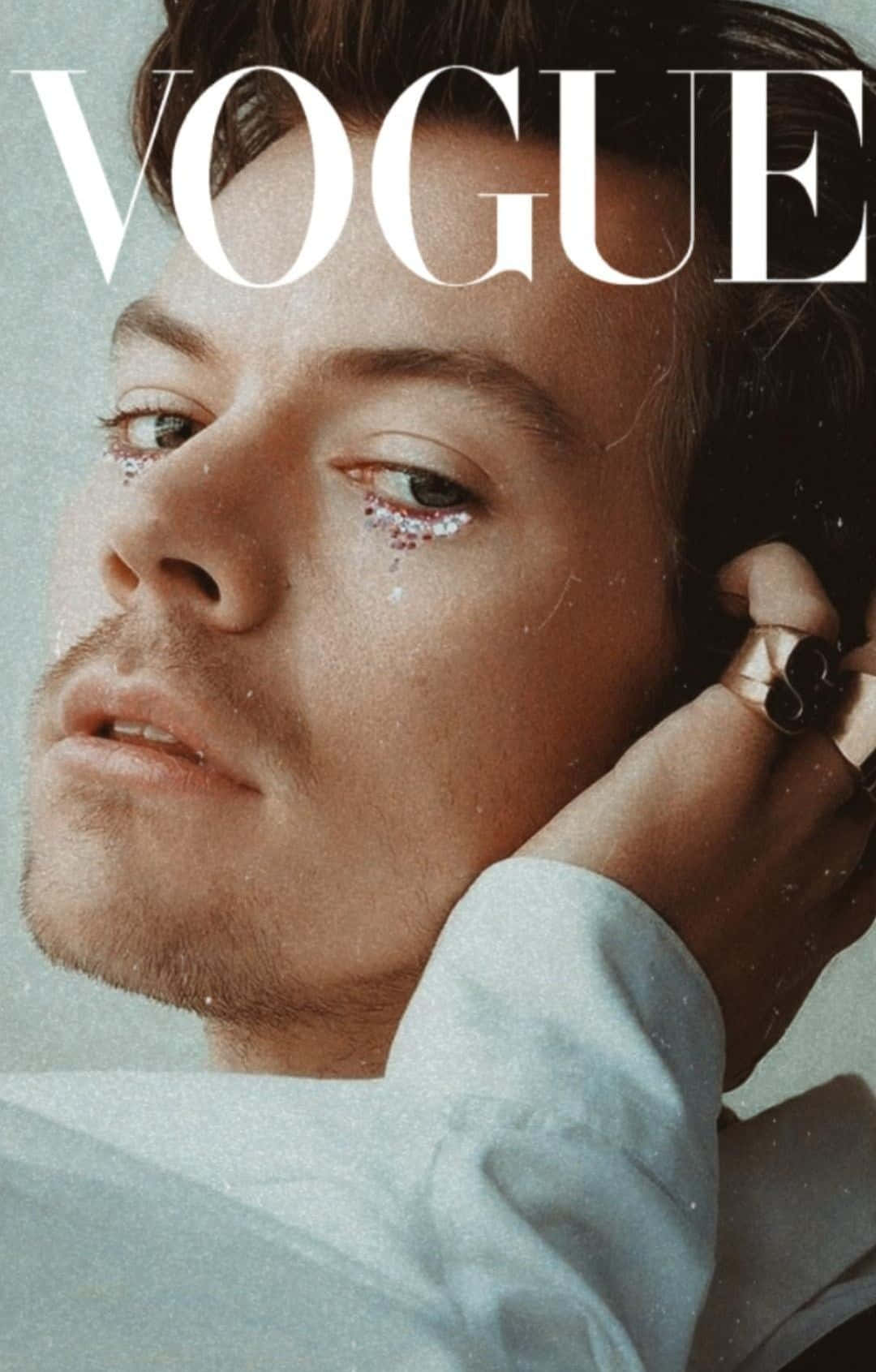 Magazine 桌布 壁紙 — 一名男子閉眼特寫肖像，眼瞼上帶有亮粉，手靠近臉部，背景是Vogue雜誌封面。