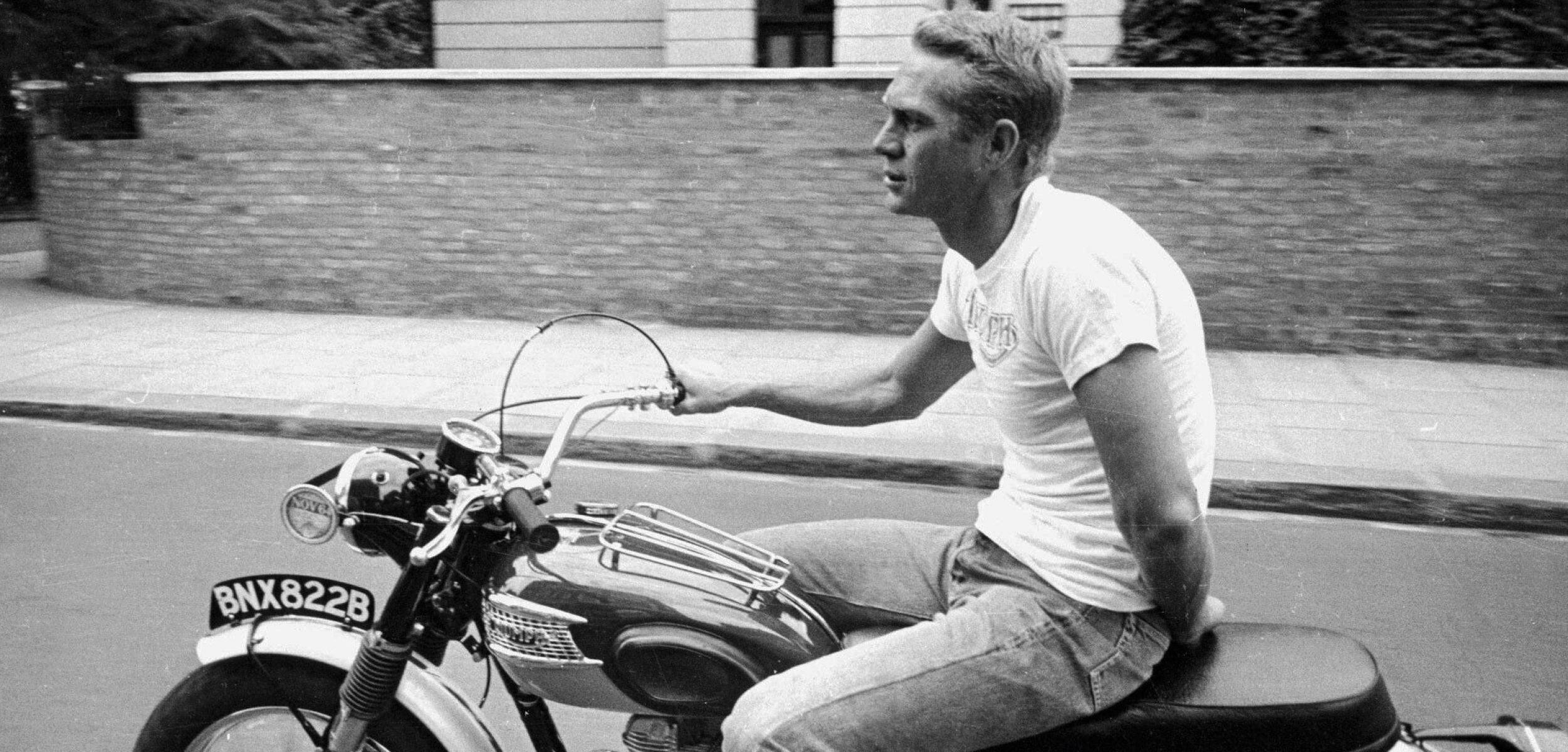 actor 桌布 壁紙 — 一名男子騎著一輛復古機車，行駛在一條背景有磚牆的街道上。