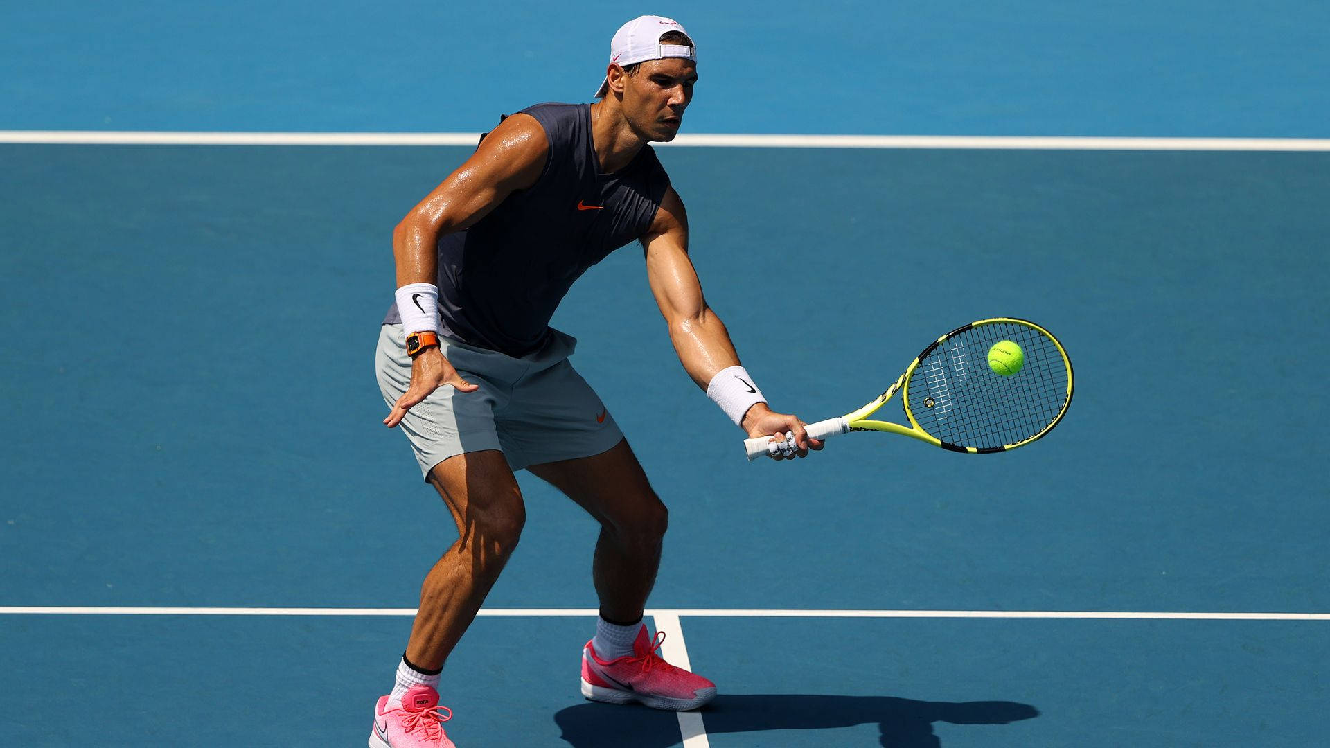 Australian Open 桌布 壁紙 — 一名男性網球運動員在充滿活力的藍色球場上揮拍擊打黃色球，專注力極強。