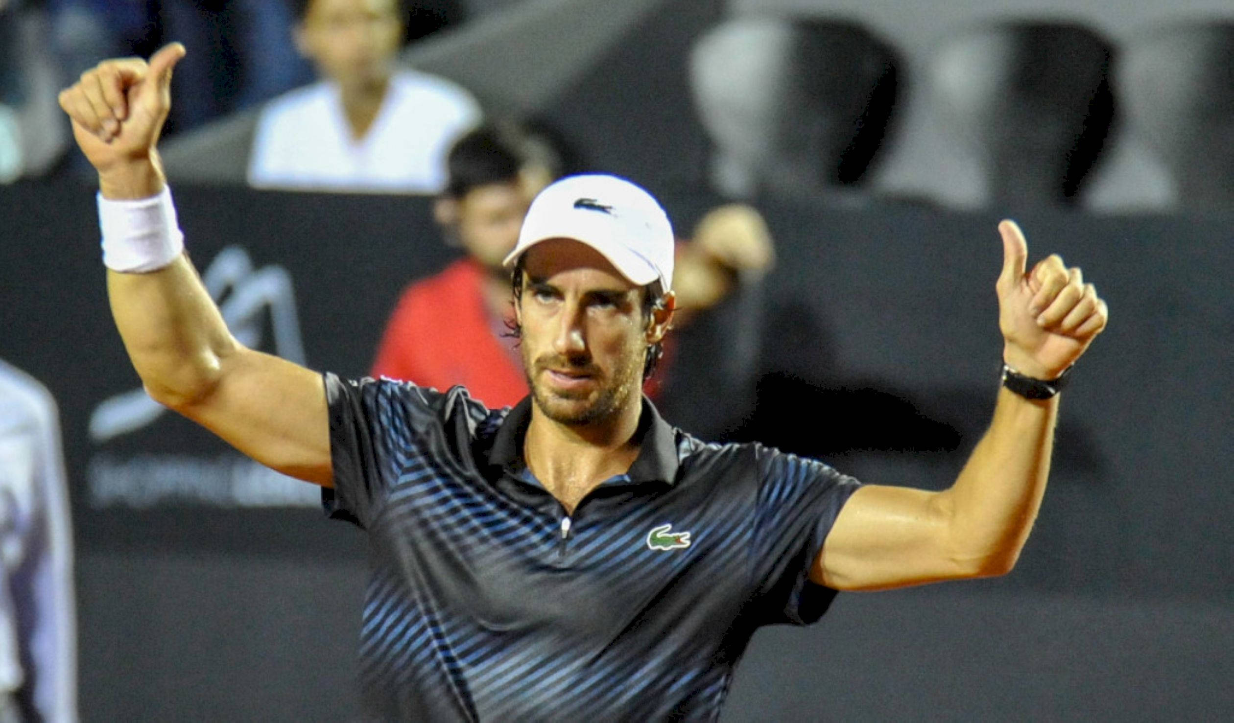 Tennis 桌布 壁紙 — 一名男性網球運動員在夜間比賽中於體育場燈光下豎起雙拇指慶祝。