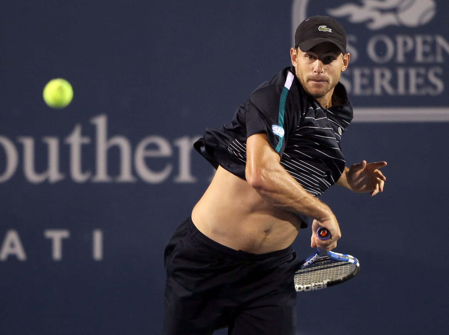 Tennis 桌布 壁紙 — 一名男性網球運動員在揮拍中擊打一個亮黃色的球，背景是深藍色的球場，上面有贊助商標誌。