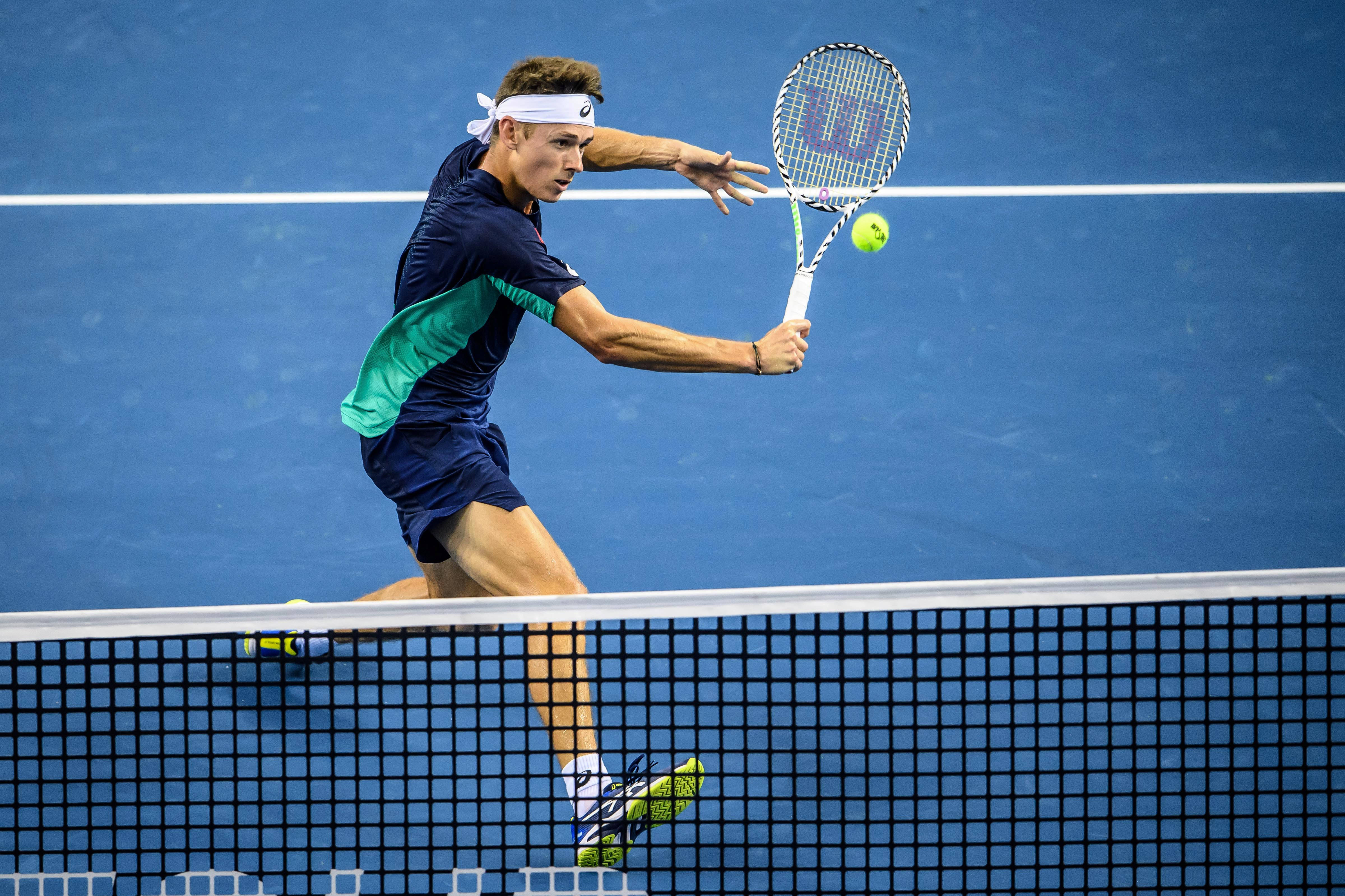 Tennis 桌布 壁紙 — 一名男性網球運動員在揮拍中途用Wilson球拍在藍色硬地球場上擊中一個黃色球。