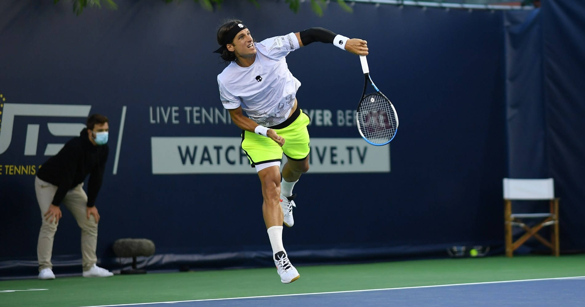 Tennis 桌布 壁紙 — 一名男性網球運動員在明亮的燈光下，於綠色球場上躍起，做出強力的正手揮拍動作。